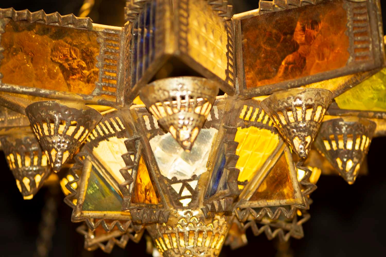 Beeindruckende Lampe, in einzigartiger volkstümlicher Handwerkskunst, Blech, gebogen und gesägt; kleine Glasplättchen in verschiedenen Texturen und Farben.
Allgemeine Form eines Sterns mit acht Spitzen, mit Platz für neun Ölgefäße,