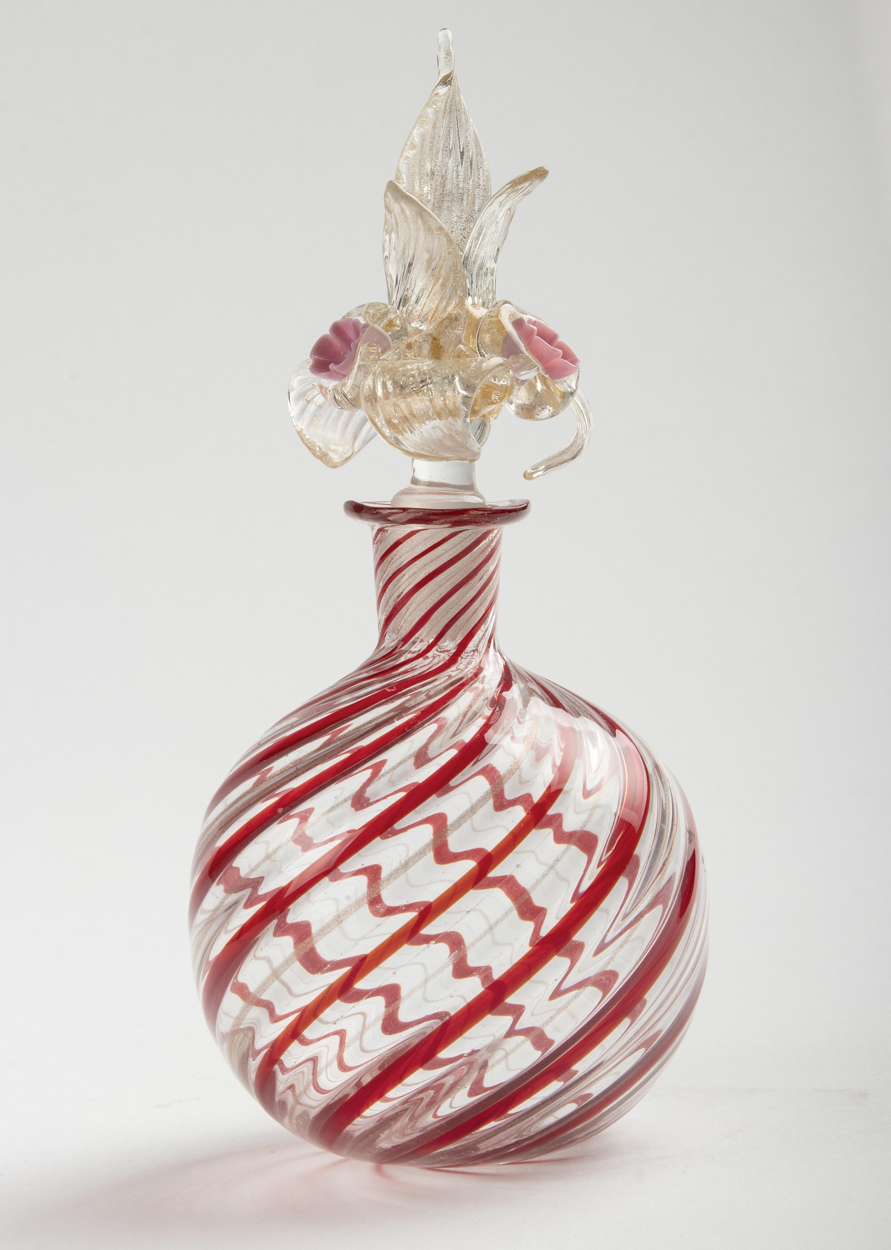 Beautiful old Murano glass bottle. The bottle has red swirls with gold colored accents. The top is beautifully decorated, typically Murano, with delicate leaves and roses. In very good condition.