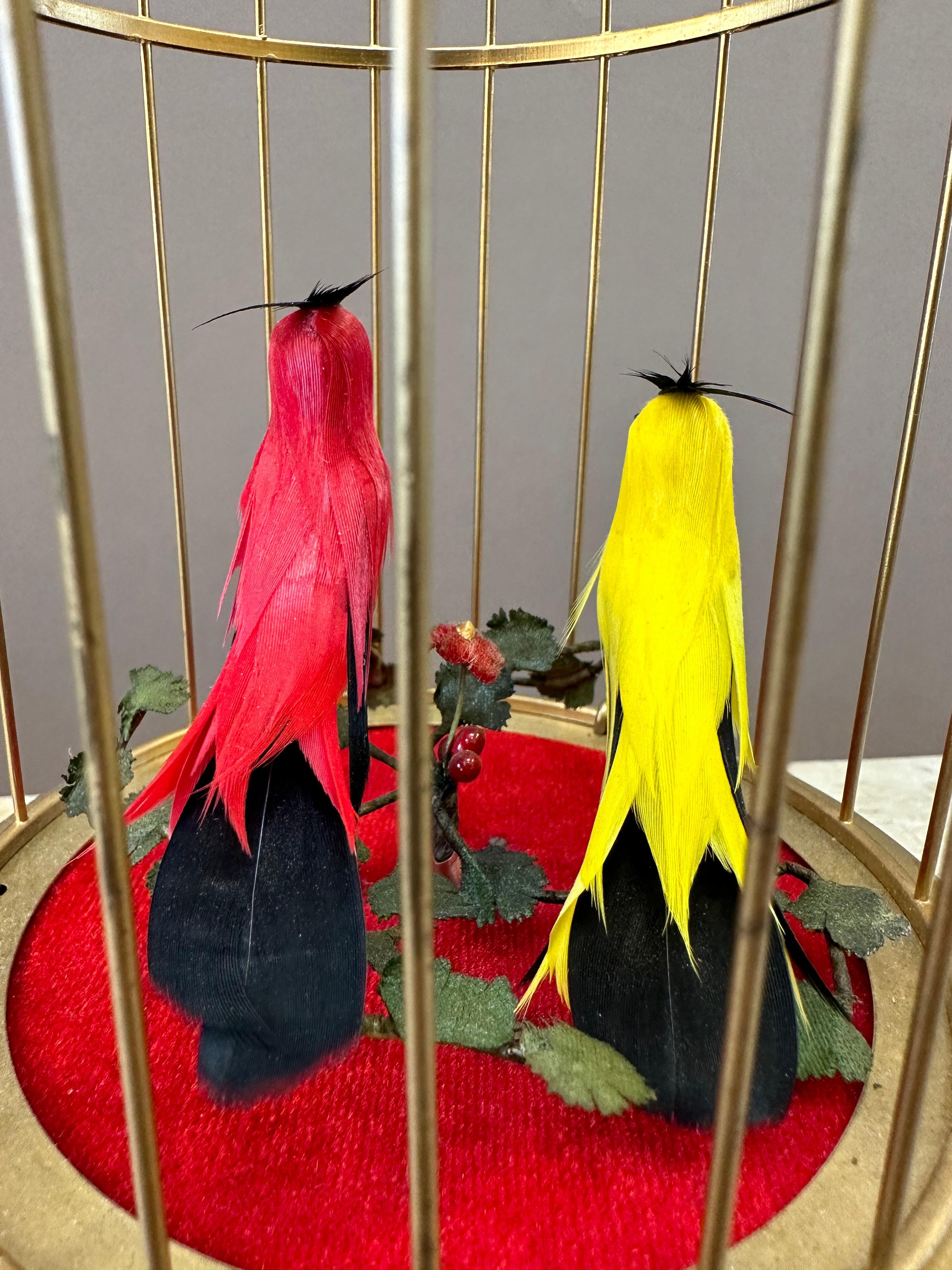 Automate à oiseaux musicaux du début du 20e siècle. Deux oiseaux chanteurs automatisés aux voix fortes et au plumage flamboyant au milieu de feuillages dans une cage en laiton doré. Les oiseaux chantent à tour de rôle. Suisse, vers 1920.    