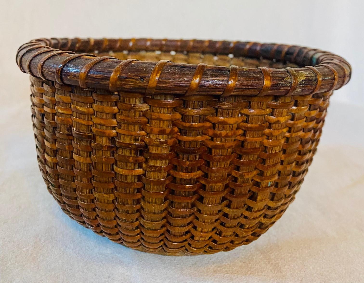 Antique nantucket basket, circa 1910, attributed to the Coffin School on Nantucket, a round open basket with cane weave on sturdy wooden staves, the slightly convex hardwood bottom plate having three scribed rings. The basket was made with no