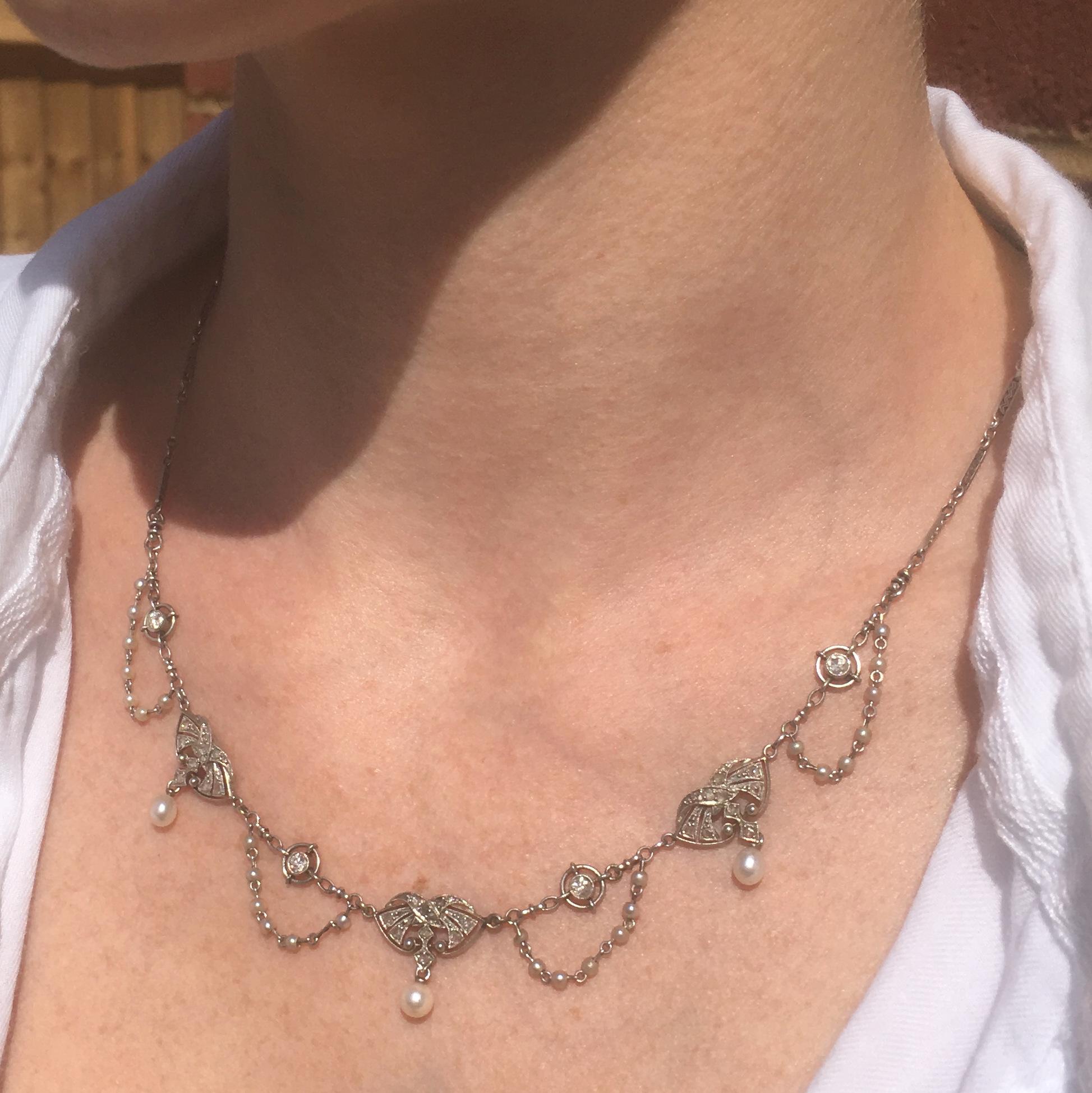 A truly special antique French necklace. This stunner, crafted entirely in platinum, features threes intricately pierced and milgrained panels each set with ten rose cut diamonds and two natural seed pearls and a further (larger) articulated natural