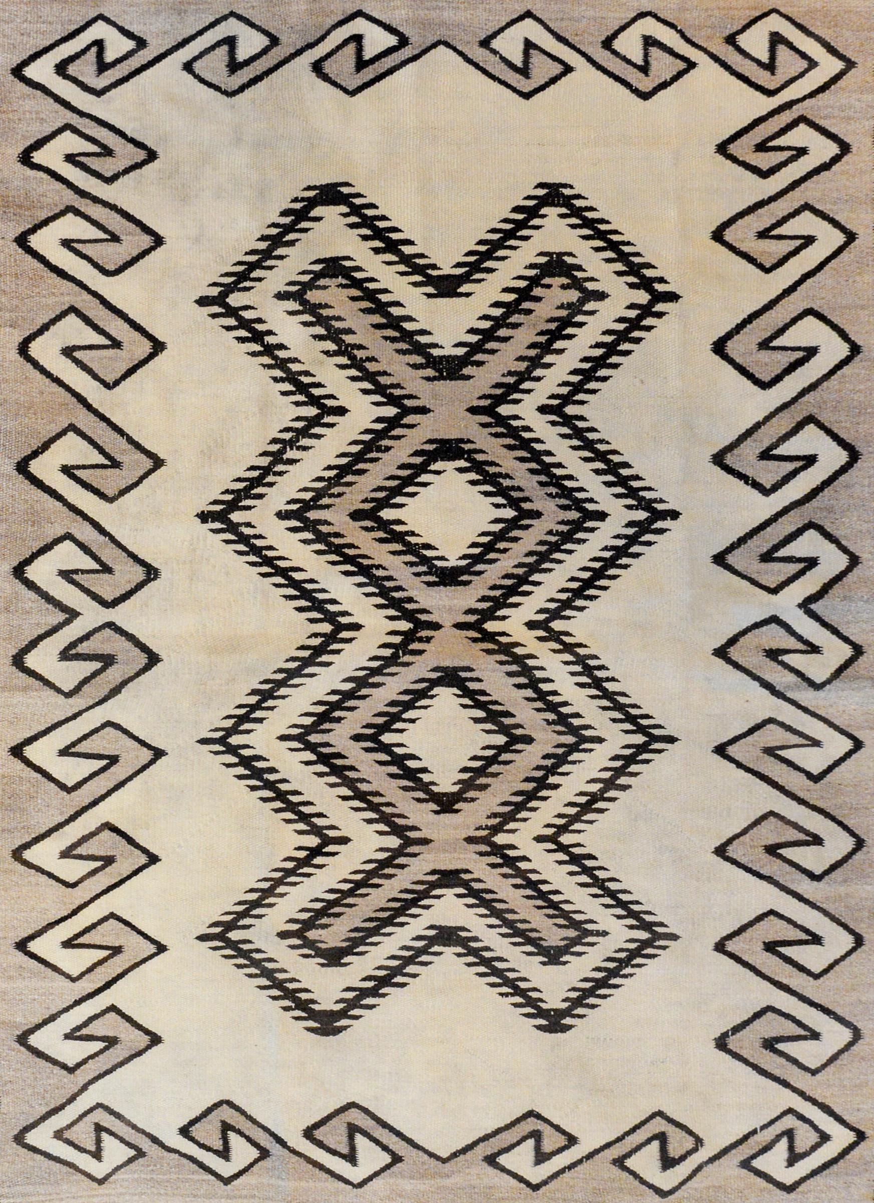 Un magnifique tissage Navajo du début du 20e siècle avec un motif géométrique audacieux à grande échelle sur le champ entouré d'une bordure complexe de vagues et d'un motif sinueux, le tout tissé en laine naturelle non teintée.