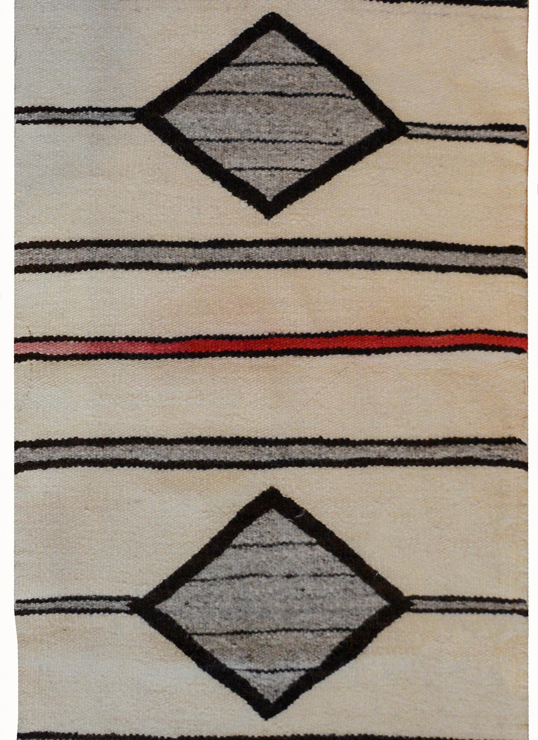 A simple early 20th century Navajo Rug with a cream colored ground, two large gray diamonds, several gray stripes edged in black, with a red stripe in the center.
