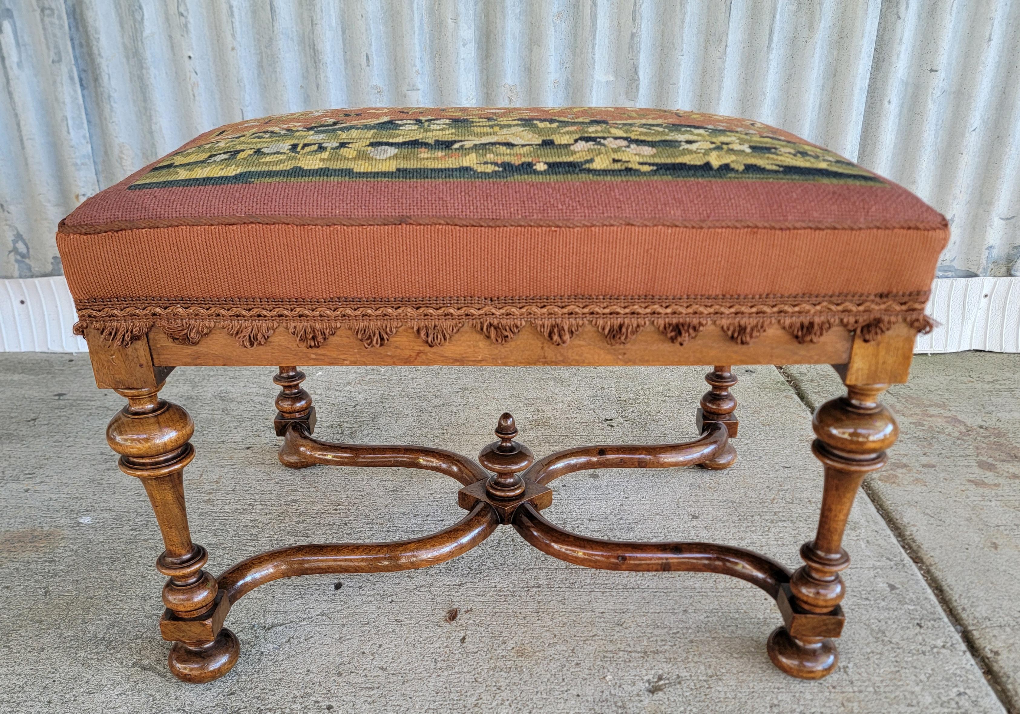 1930's William & Mary style footstool. Period hand needlepoint cover with birds and floral detail. Refinished base with excellent craftsmanship and detail to upholstery. Measures 18 inches deep, 24 inches wide.