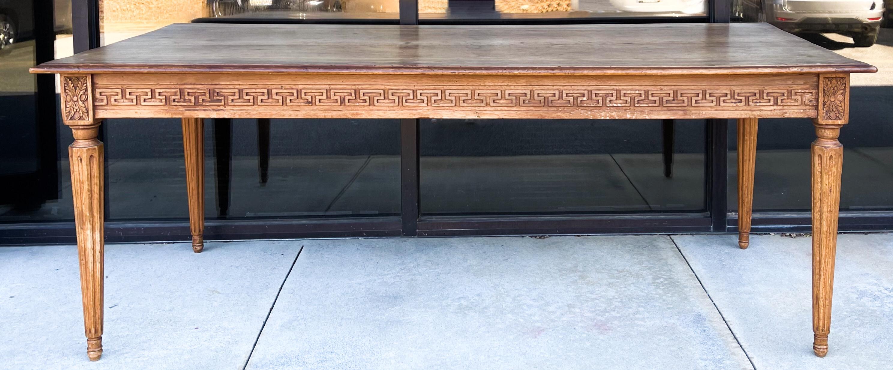 This is an ea,y 20th century neo-classical style Italian carved walnut farm table. It has two plank construction and butterfly joints. It is stamped on the underside.