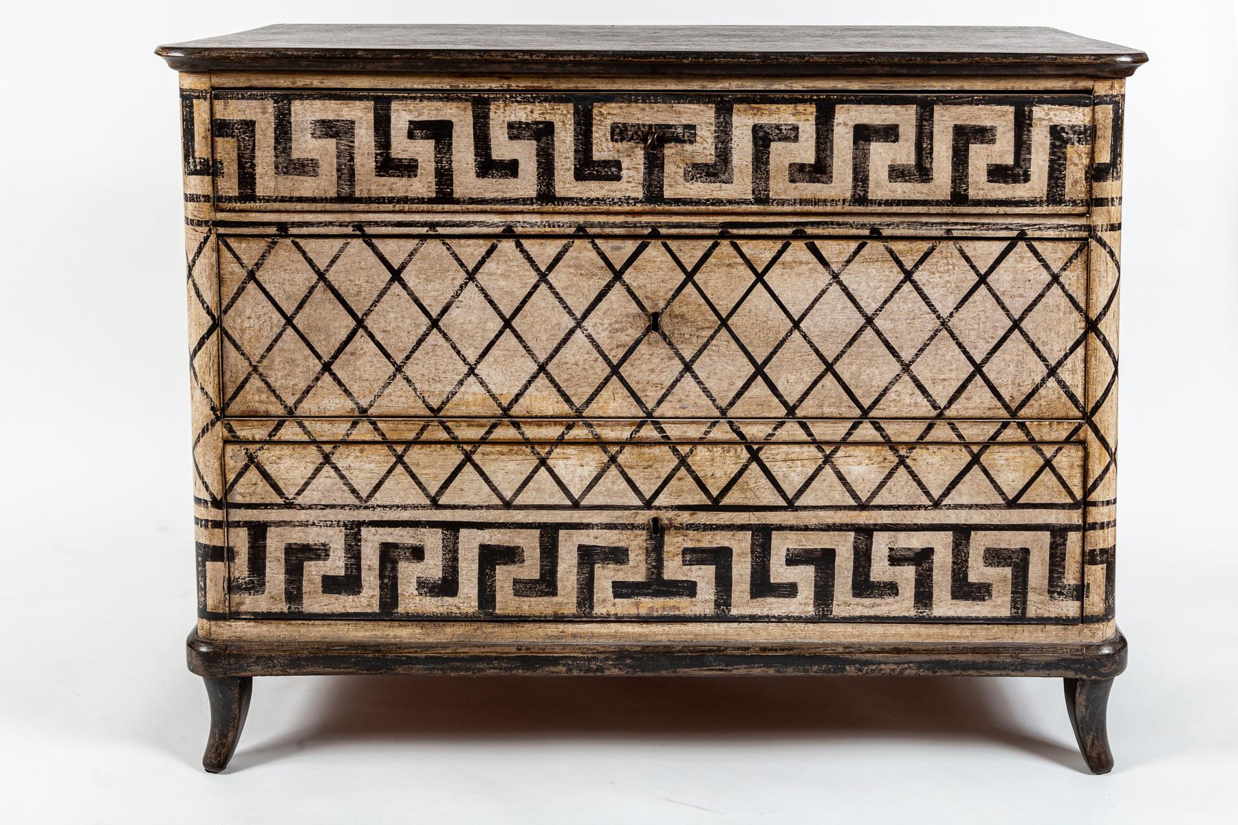 Questa bella cassettiera dipinta in stile neoclassico, composta da tre lunghi cassetti che poggiano su robuste gambe strombate, è ornata da un armonioso disegno a chiave greca in una finitura dipinta in nero e crema dai toni molto caldi e anticati. 