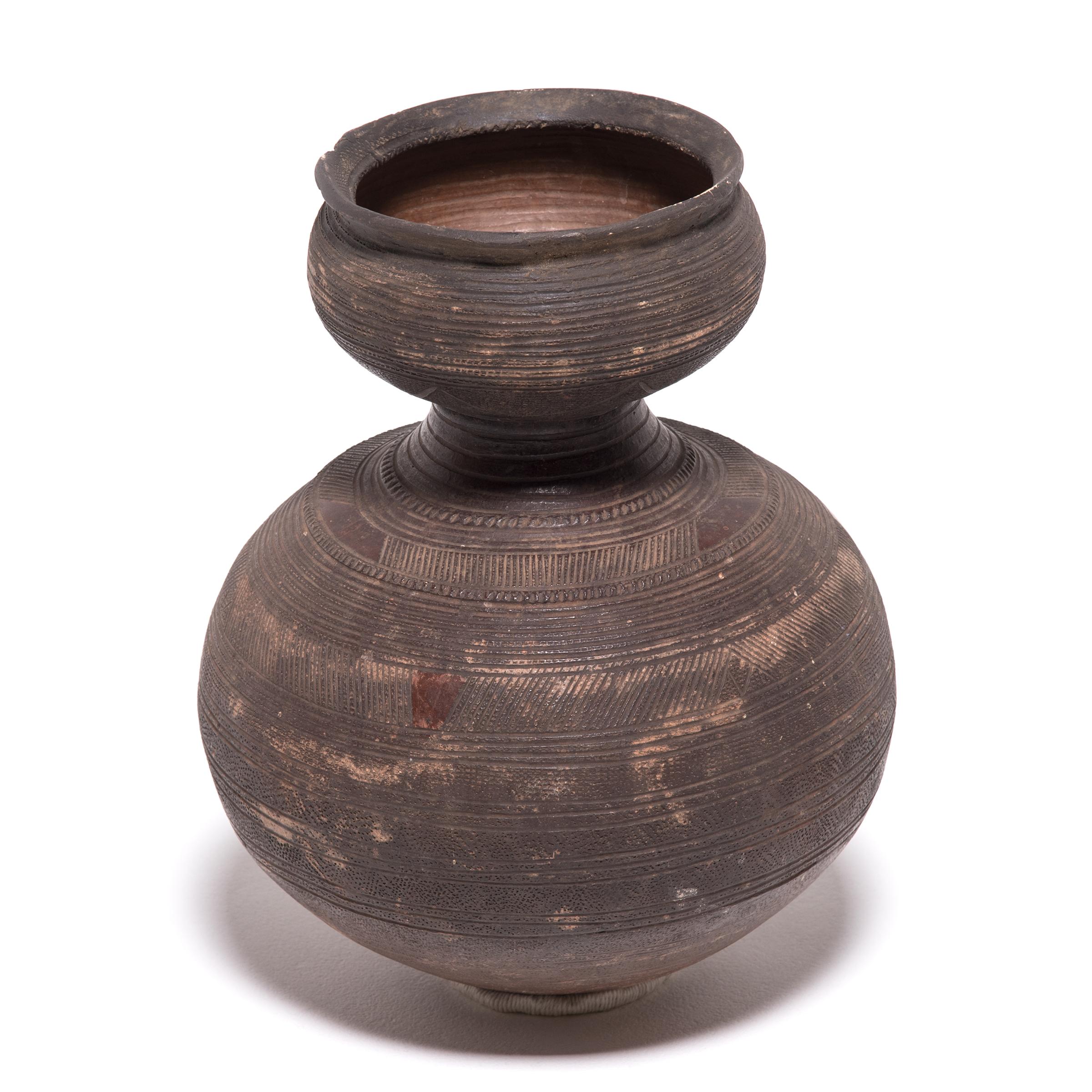 Inspired by the natural world, Nupe ceramicists fired this water vessel in the shape of a gourd. The vessel's varied surface textures and colors come from its functional design. The dimpling and geometric markings were engraved to give the drinker a