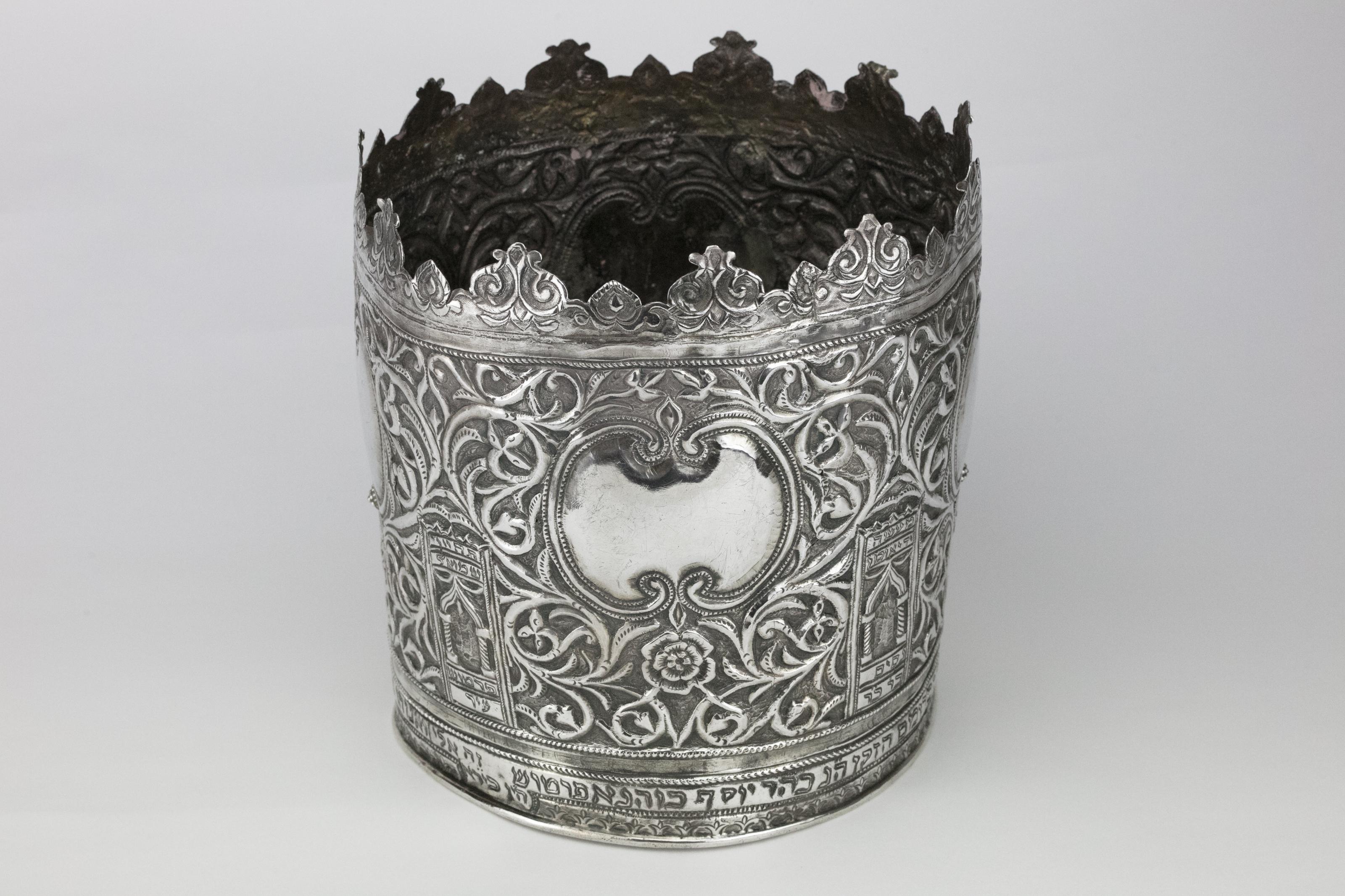 Large silver Torah crown, Probably Tunisia, 1922. 
Hand chased. Decorated with scrolling designs, arched pillars, reflective cartouches, flowers and organic design. 
The lower rim is engraved in Hebrew 