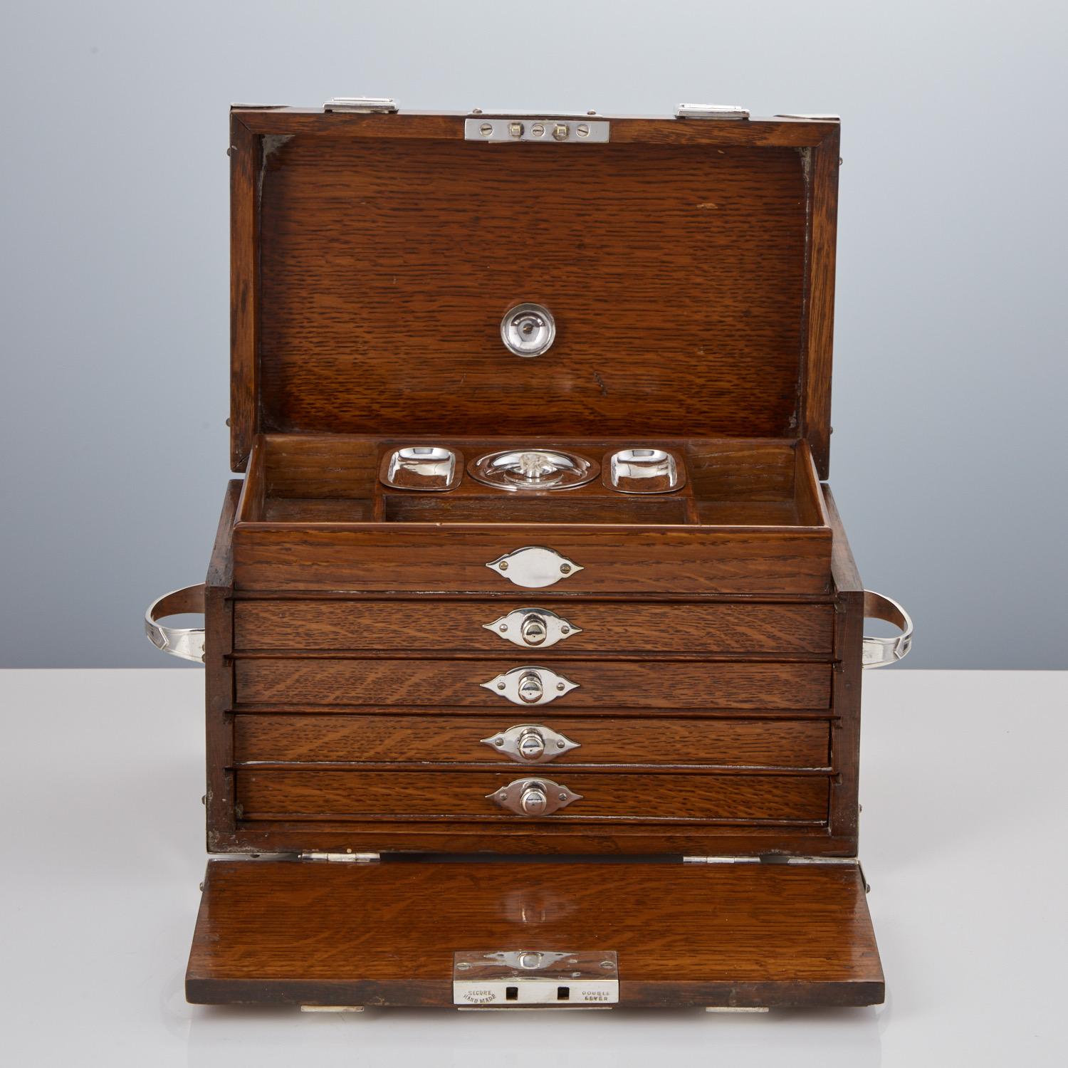 This beautiful english oak box is extremely well made and enhanced by the strap & buckle features which also applies to the carrying handles.
On lifting the lid it reveals a central cigar lighter with two small trays either side for matches, there