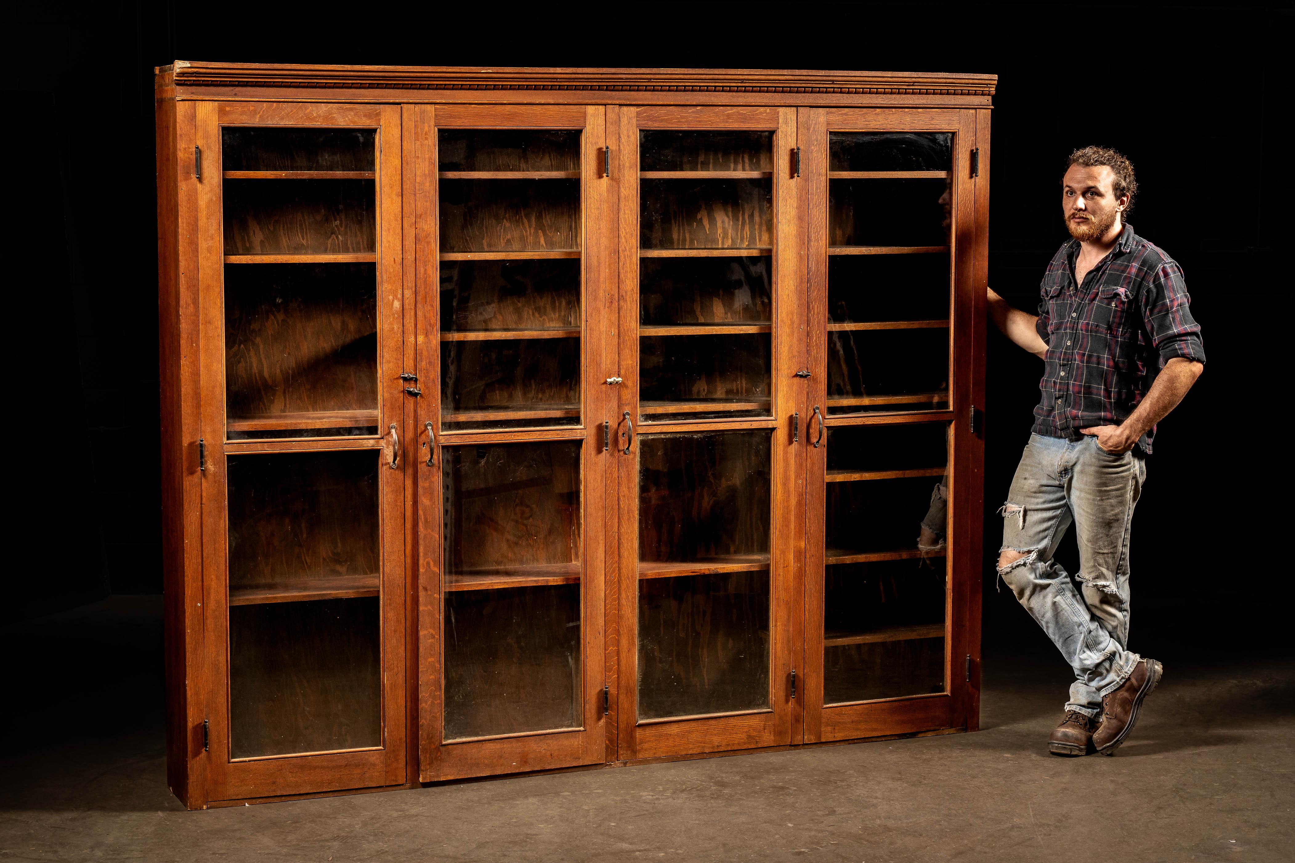 Antique wooden display with cabinet-height swing out wavy glass doors.

This impressive piece is of solid oak construction and features large doors with wavy glass panes that open to allow access to the large interior storage area. Within the