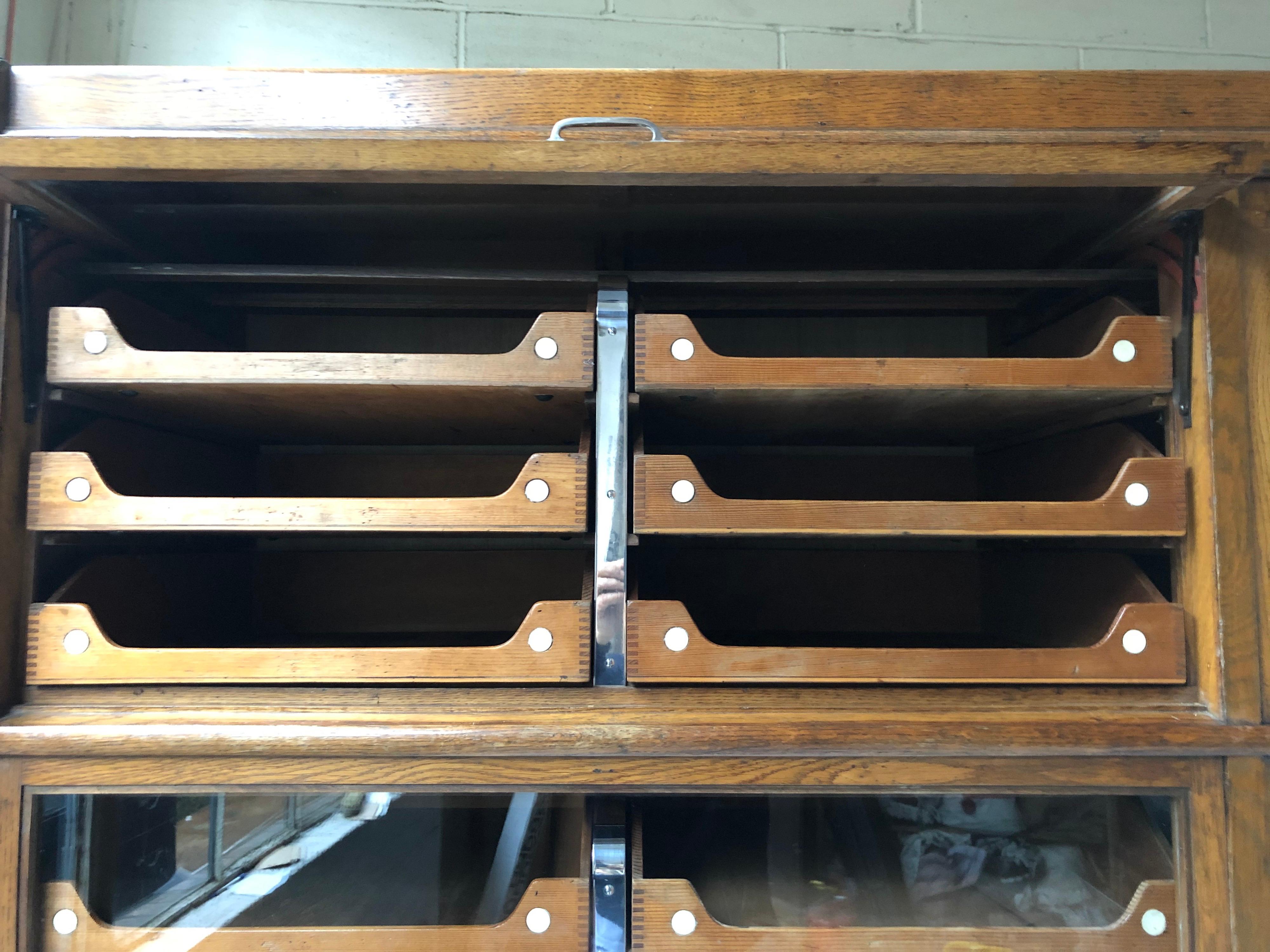 Early 20th century oak with six rising glazed doors enclosing 32 sliding trays above six drawers stamped “Pollards London and Glasgow” and patents.