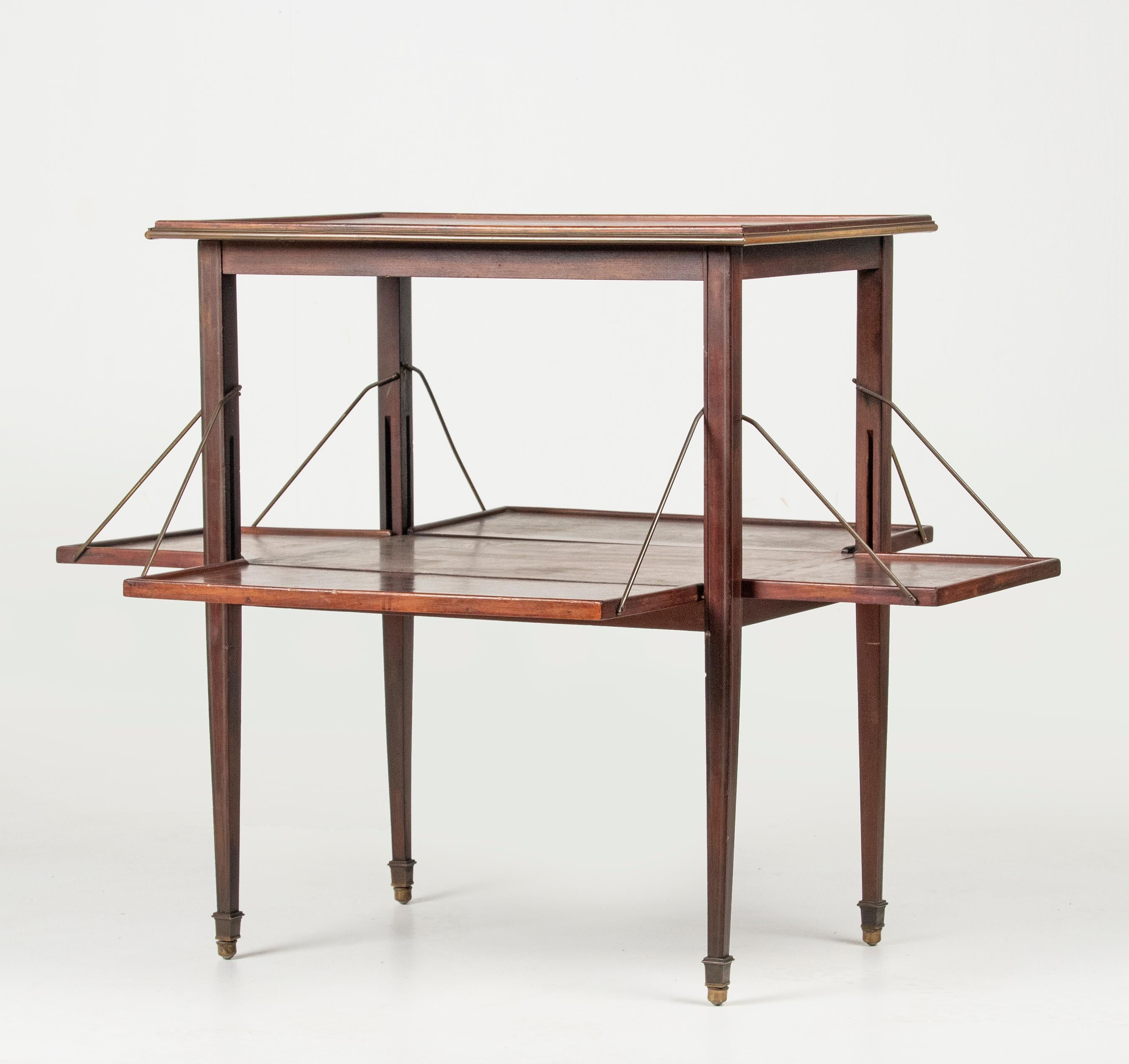 An oak serving table. Ideal for, for example, displaying the liqueurware, coffee or tea porcelain. The trays are made of veneered oak, in a cubic motif. The top part have a brass rim. The legs are inlaid with brass and rest on brass legs. The lower