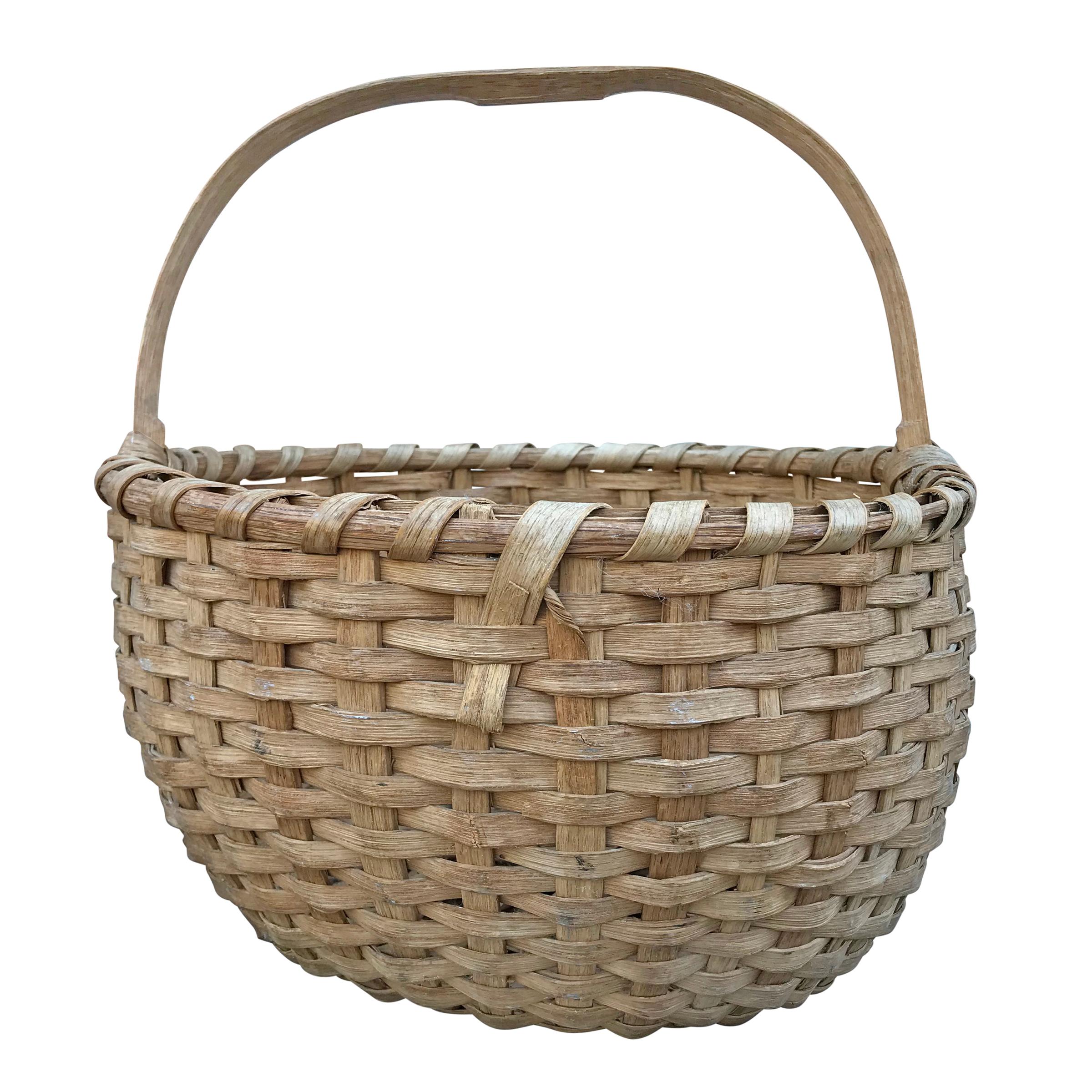 A wonderful early 20th century hand-woven oak splint gathering basket with a single bent oak handle, a double banded rim, and a lovely wonky shape. Found in Wisconsin.