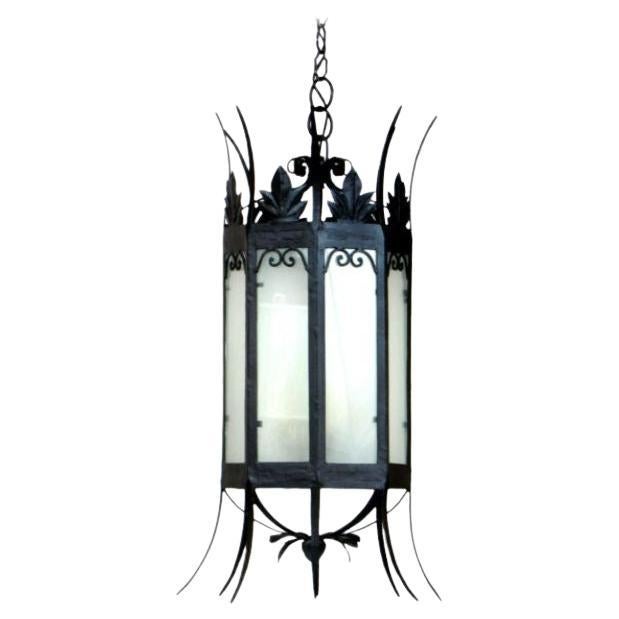 Dramatic wrought iron lantern. United States, C. 1920 Octagonal lantern with interior sandblasted glass panels. Wrought iron frame is delicate for it’s size with foliate crown and petals on the bottom. Lit from the inside by a four light cluster of