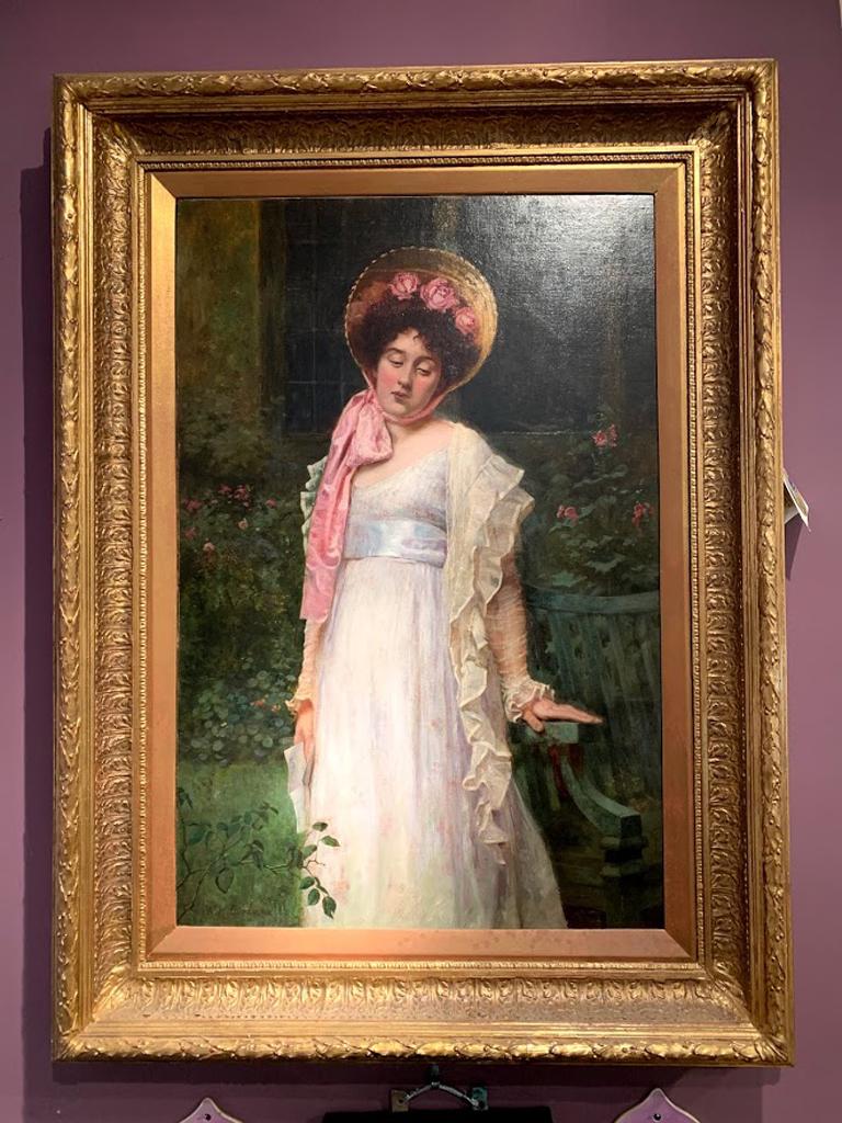 Originales englisches Öl auf Leinwand aus dem frühen 20. Jahrhundert, das eine junge Dame in einem Garten zeigt, die ein weißes Kleid mit passendem Schal und eine Haube mit rosa Rosen und Schleife trägt und einen Brief in der rechten Hand hält. Das