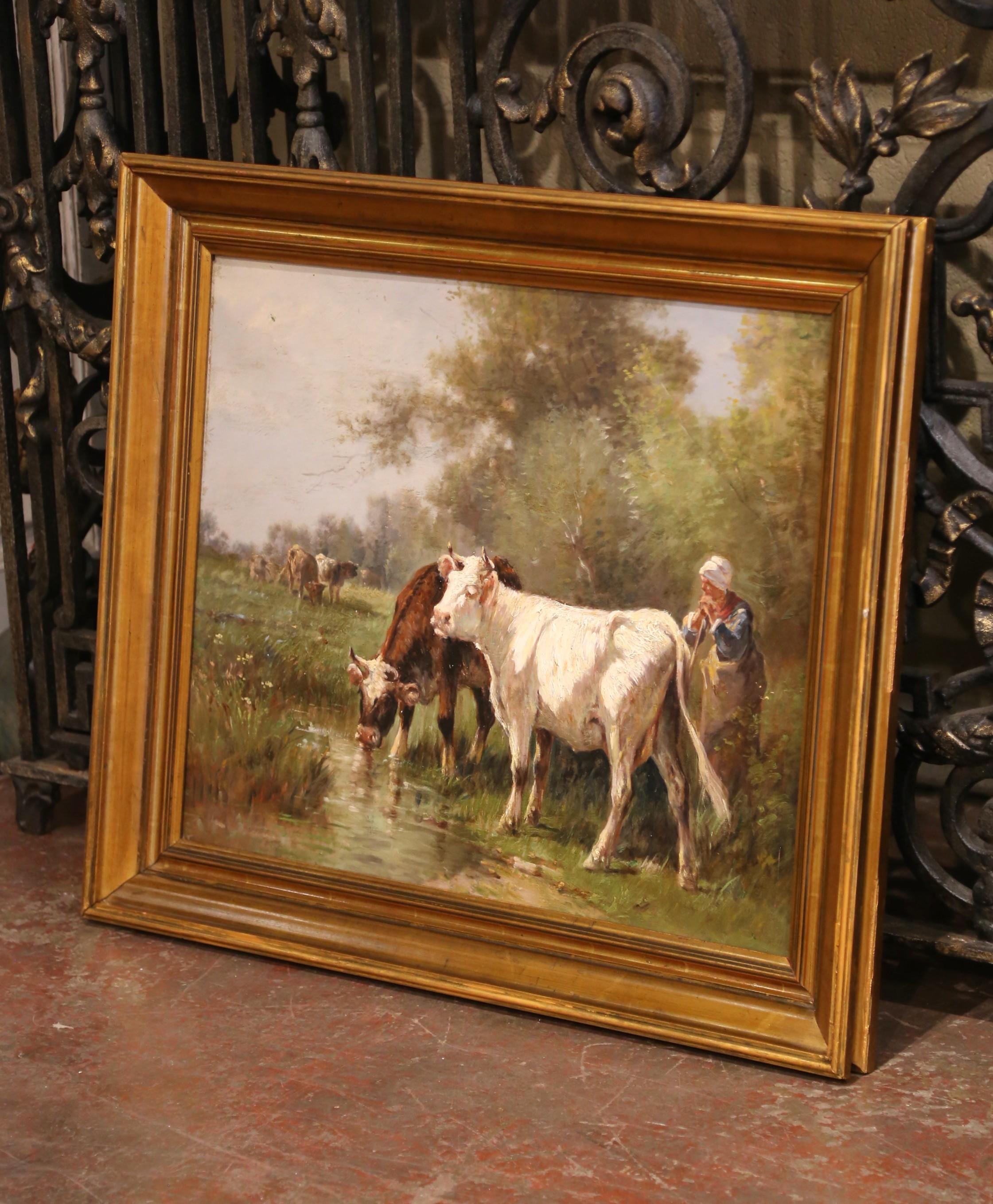 Rendered with pastoral charm and naturalistic detail, this early 20th-century oil painting depicts a tranquil rural moment as a young farm girl tends to her cattle by a stream. Executed in oil on canvas and housed in a molded giltwood frame, the