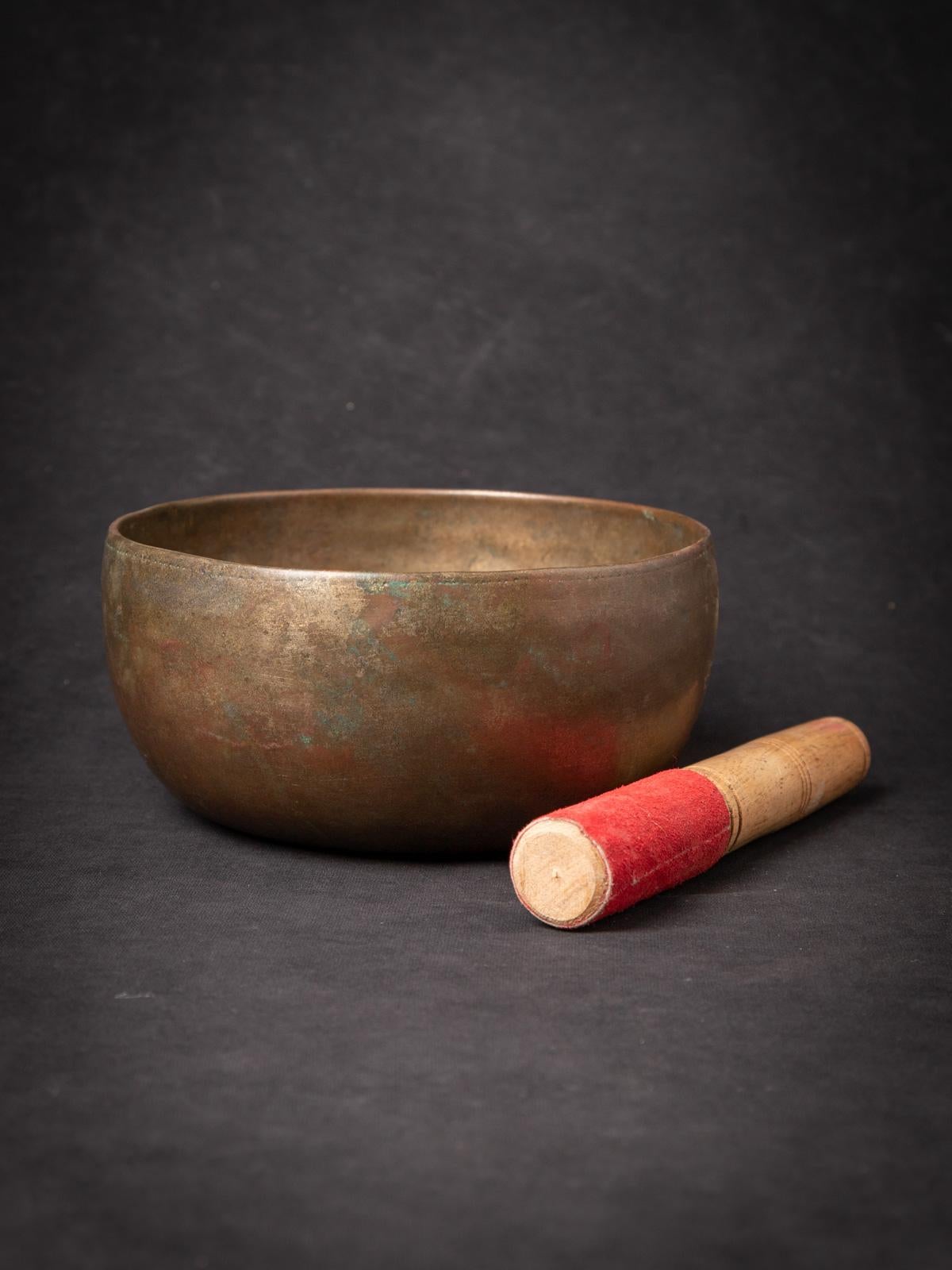 Discover the enchanting tones and meditative vibrations of this Old Bronze Nepali Singing Bowl. Crafted from bronze, this exquisite bowl stands at 8.6 cm in height with a diameter of 18 cm. Its age lends it a unique character, dating back to the