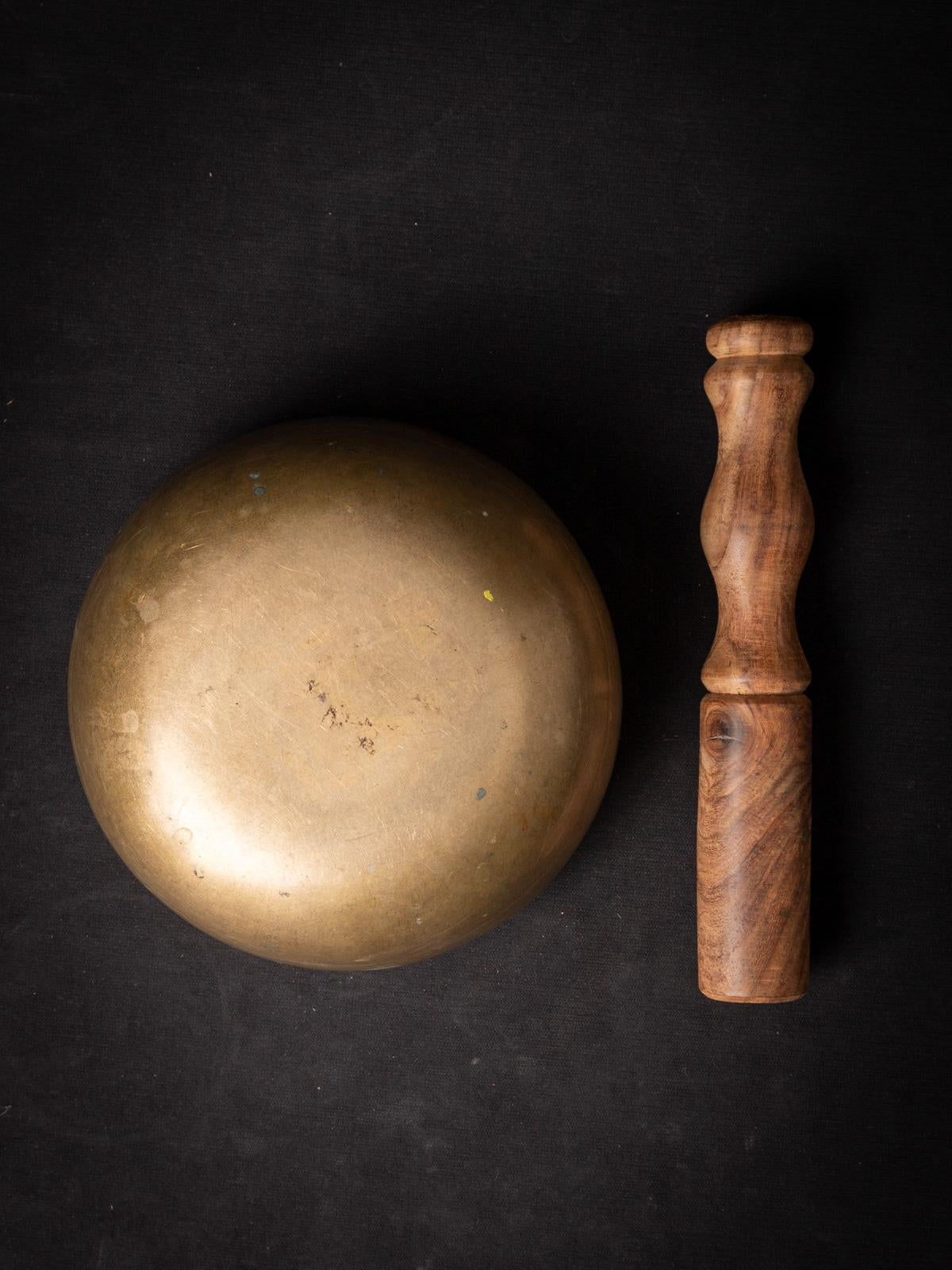 The old bronze Nepali Singing Bowl is a captivating artifact crafted from durable bronze, known for its rich sound and spiritual significance. Standing at a height of 7.4 cm and boasting a diameter of 15.3 cm, this bowl emanates a sense of mystique