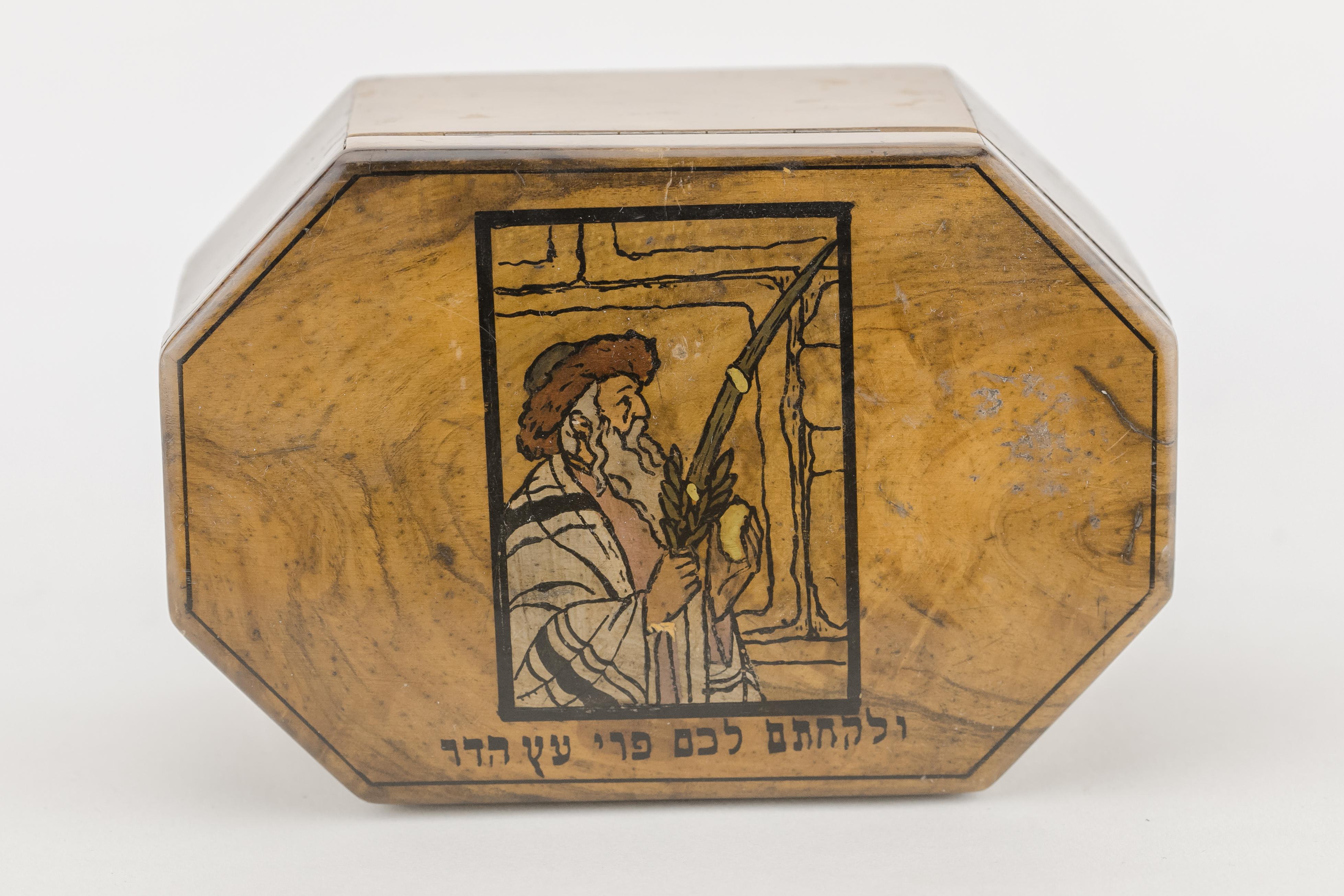 Hand painted olive wood Etrog box by Bezalel school Jerusalem, circa 1910. 
Unique octagonal shape. Decorated with a scene of a Jew holding and blessing on the four species at the Kotel during Sukkot, and bearing Hebrew text below: 