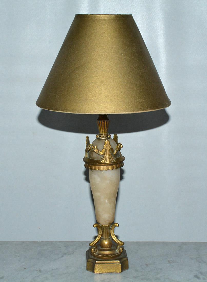 The elegant petite early 20th century neoclassical table lamp is composed of a smooth onyx base trimmed with gold metal features at top and bottom. Push switch, electrified for US use.  The gold lampshade is included but it is not new and is in