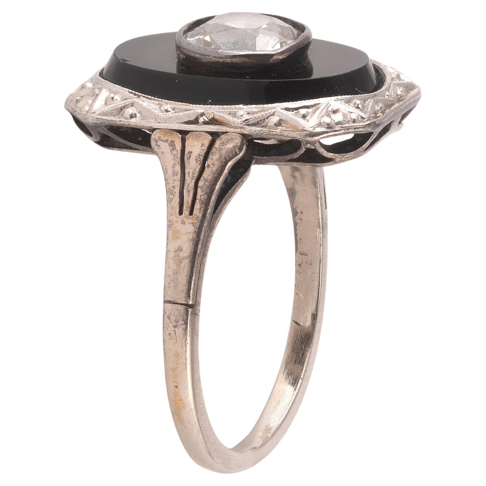 The oval shaped flat onyx inset with a collet set principal round old cut diamond, approximately 1ct.
Length of head 1.7cm x 1.2cm
The setting is in platinum with geometric motif engravings, typical of the early 1900s.
Size: 6
Weight: