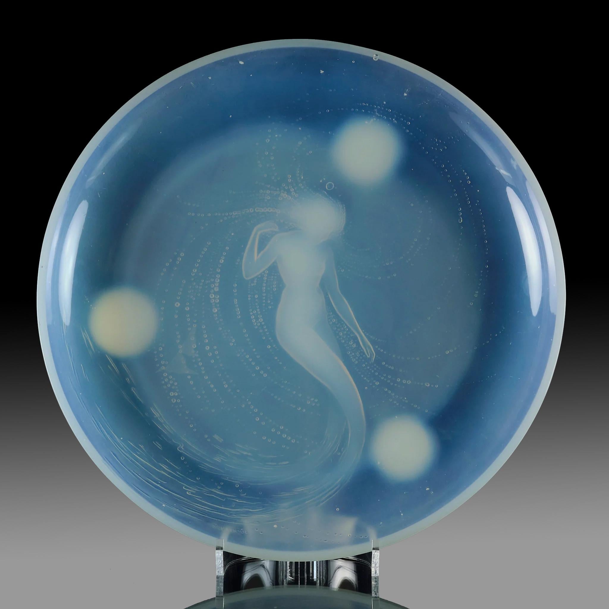 An exceptional frosted glass salver with raised deep opalescent design of a beautiful mermaid in a swirling watery landscape, the three large bubbles around her protruding from the underside to act as feet, signed R Lalique

Sirène
Catalogue