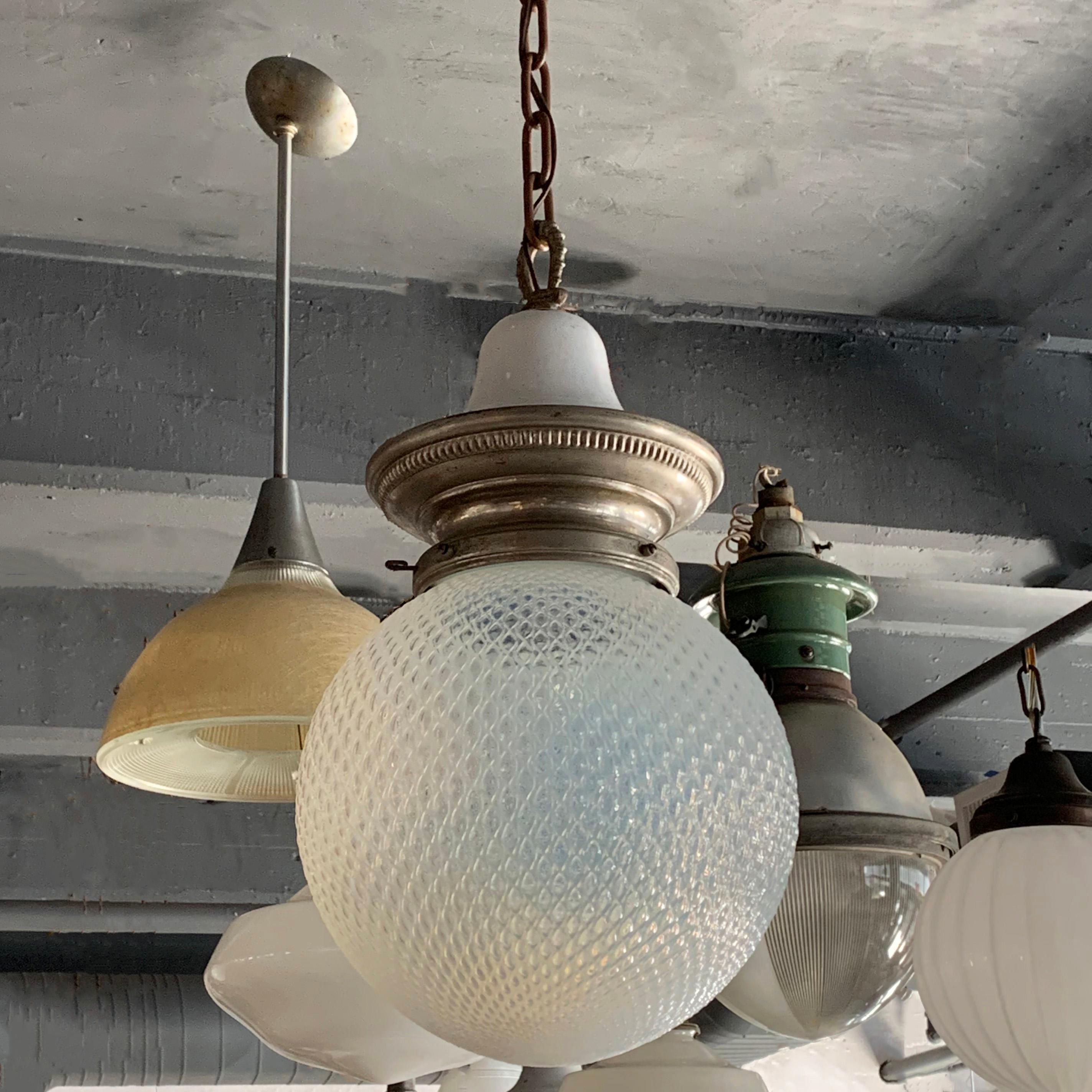 Early 20th century, library pendant light features a patterned, opaline glass globe shade with nickel-plated brass and porcelain enameled crown fitter, brass chain and canopy is wired to accept up to a 300 watt bulb. The overall height is 48 inches