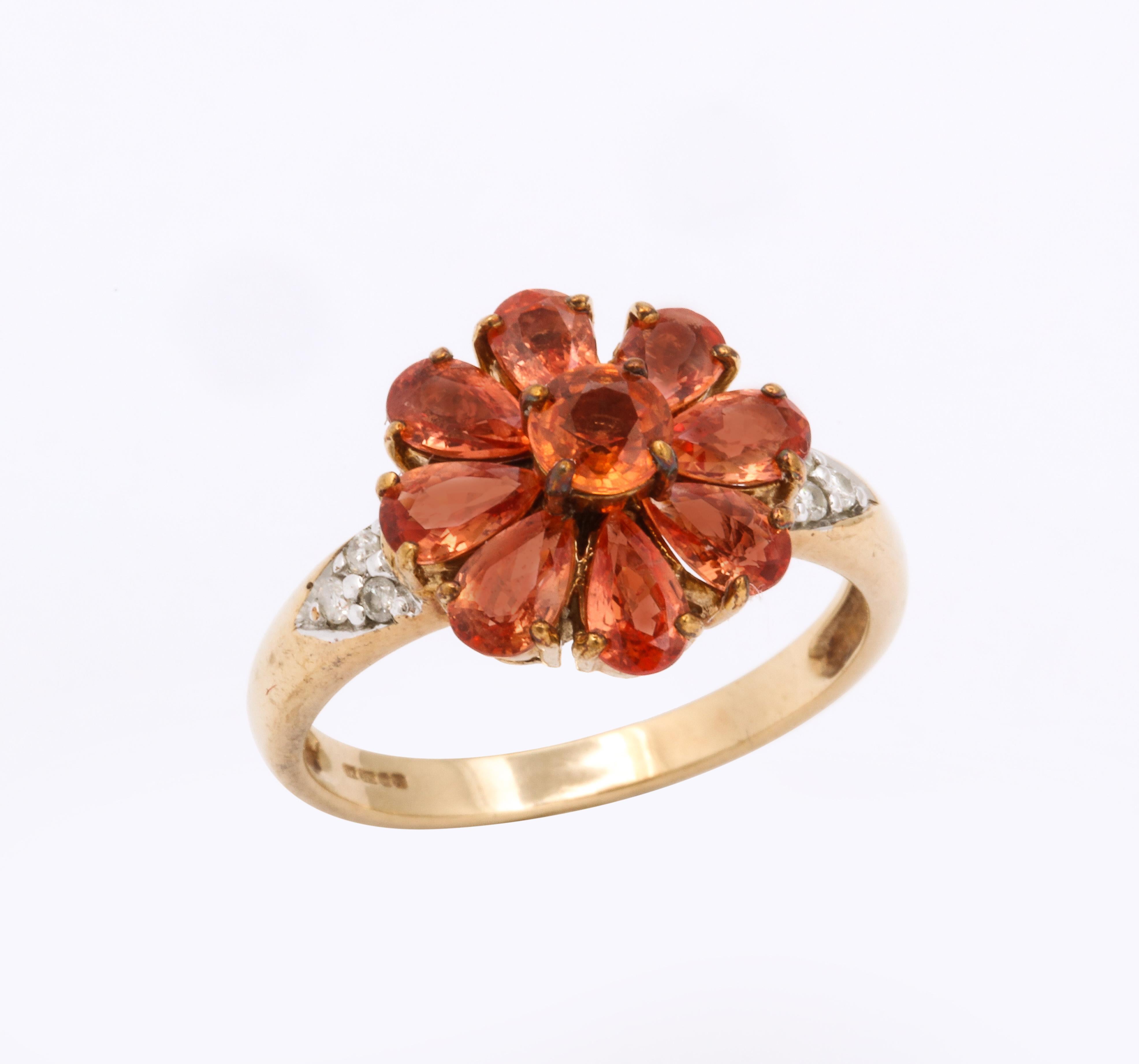 The color of the pear shaped sapphires in this 1907 ring is a honey orange bronze. That is the best color description I can come up with the saturated orange gems. The form is a floral daisy which calls forth the memory of she/he loves me or loves