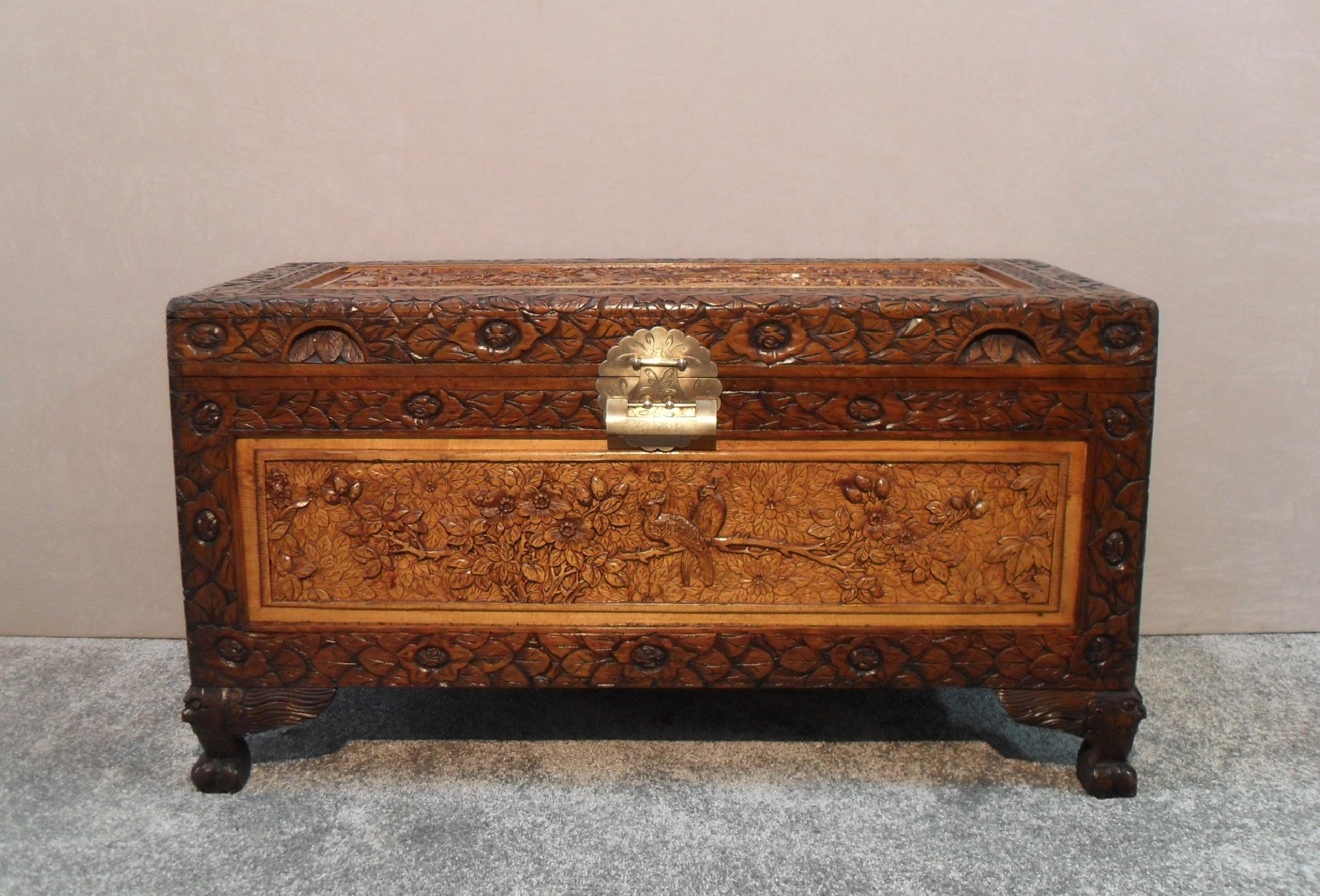 An extremely good quality Oriental freestanding teak chest with beautifully carved inset maple panels of birds and flowers to all four sides and top stood on cabriole feet. The chest retains it original engraved brass back plate and latch and comes