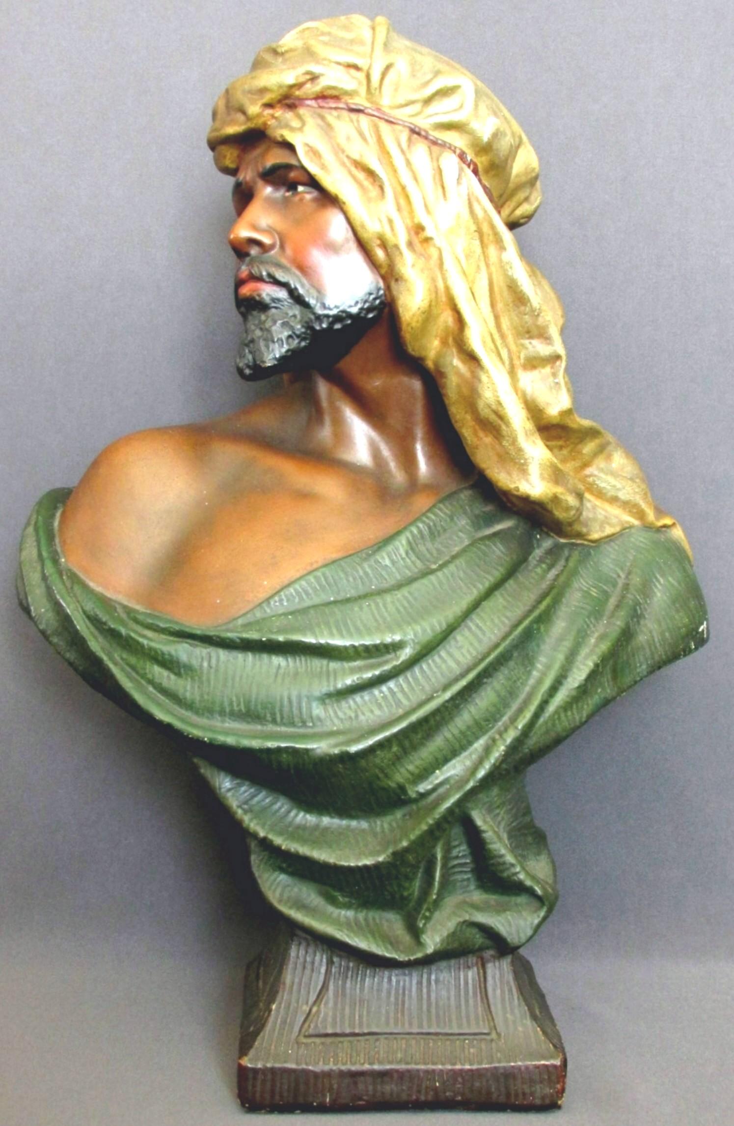 A highly decorative profile portrait bust of a bearded Moor attired in traditional garb, painted in polychrome detail and modelled in the manner of Friedrich Goldscheider but unsigned.
 