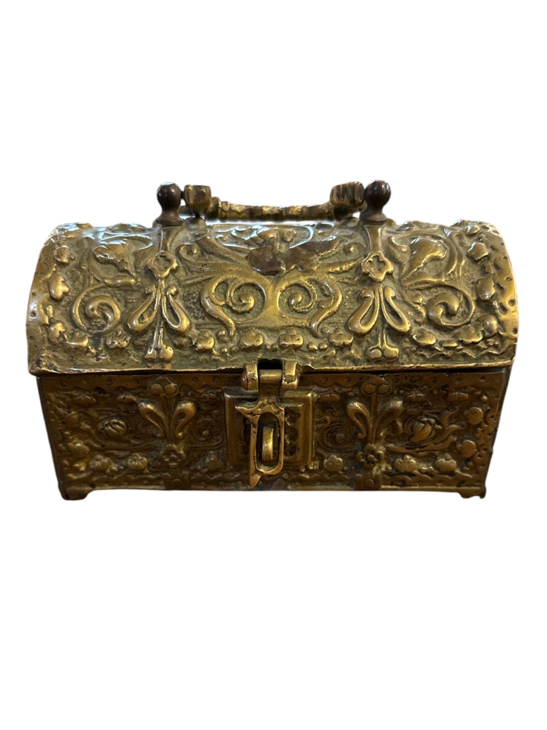 Ajoutez une touche d'élégance intemporelle à votre Collectional avec cette boîte à bijoux en laiton orné du début du 20e siècle. D'une facture exquise, cette pièce présente des motifs floraux et des volutes en repoussé qui s'enroulent gracieusement