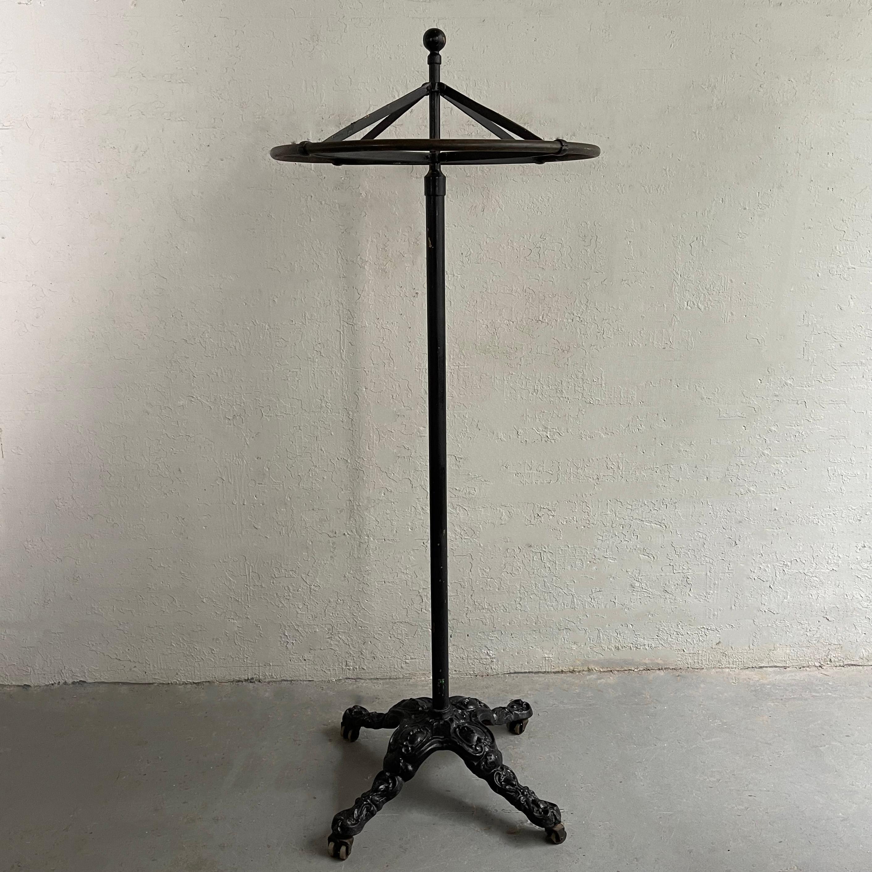 Early 20th century, industrial, cast iron rounder garment rack features a 30 inch round rotating rack on a rolling stem with ornate base. The round rack separates from the stem for transport.