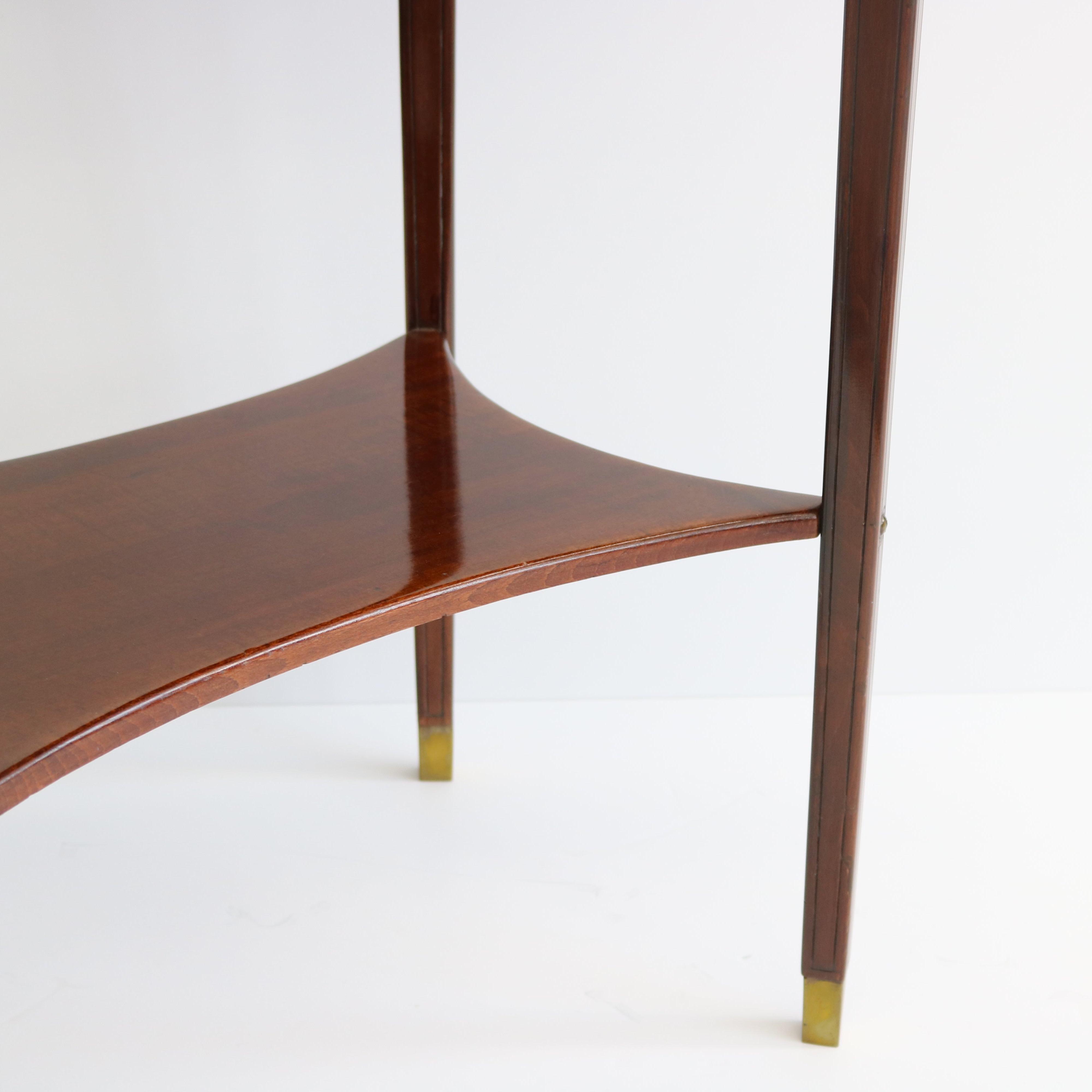 Mesa ovalada de dos pisos de la Secesión vienesa, procedente de Austria, hacia 1905. Madera de haya teñida sobre cuatro patas cónicas con sabots de bronce patinado. Fíjate en el peculiar estante inferior, que presenta un borde cóncavo en cada uno de