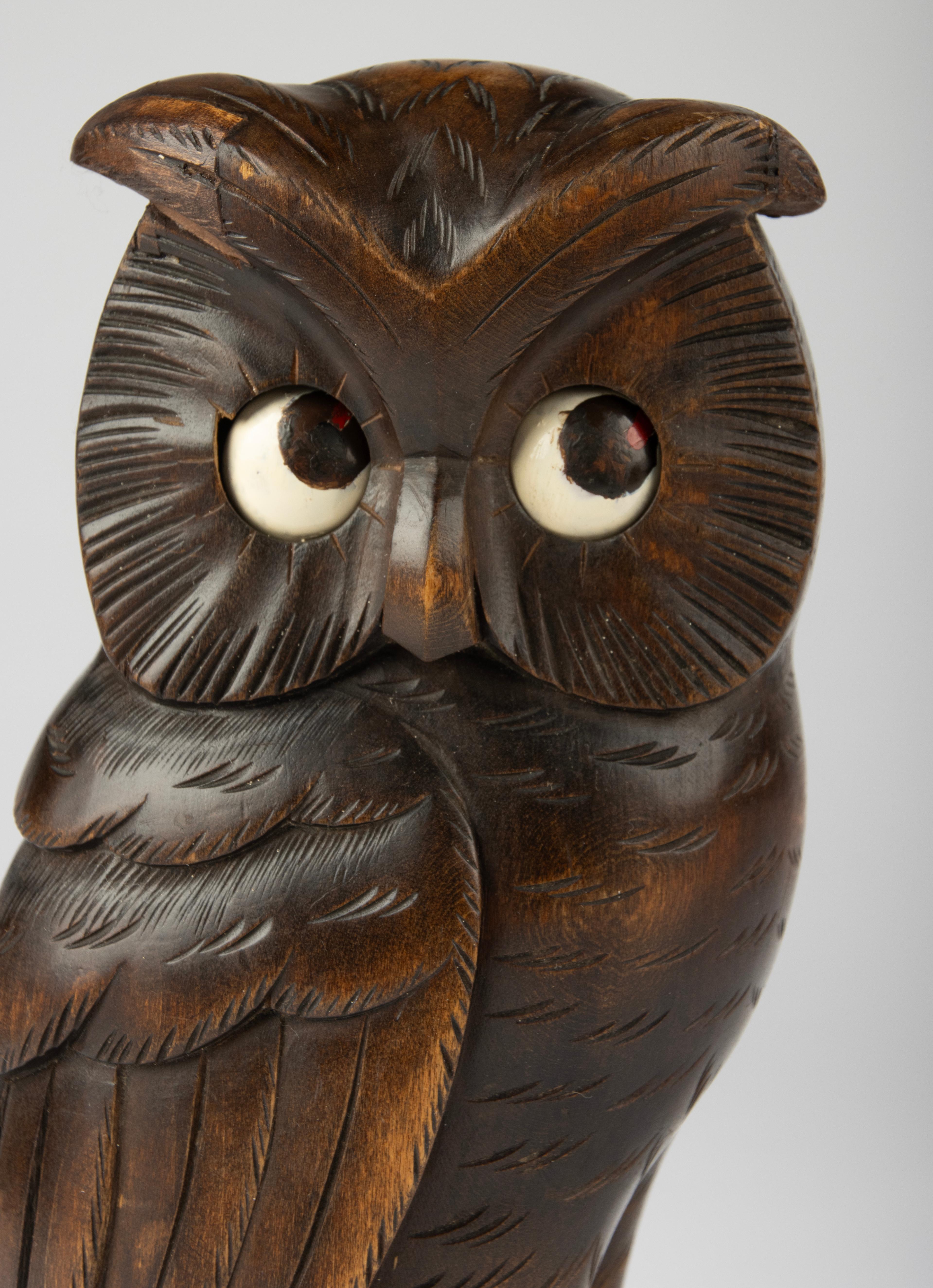 Charming early 20th century novelty clock in the shape of an owl, likely originating from the Black Forest region in Germany. Expertly hand-carved from dark-stained wood, this whimsical piece is characterized by its large expressive eyes, which