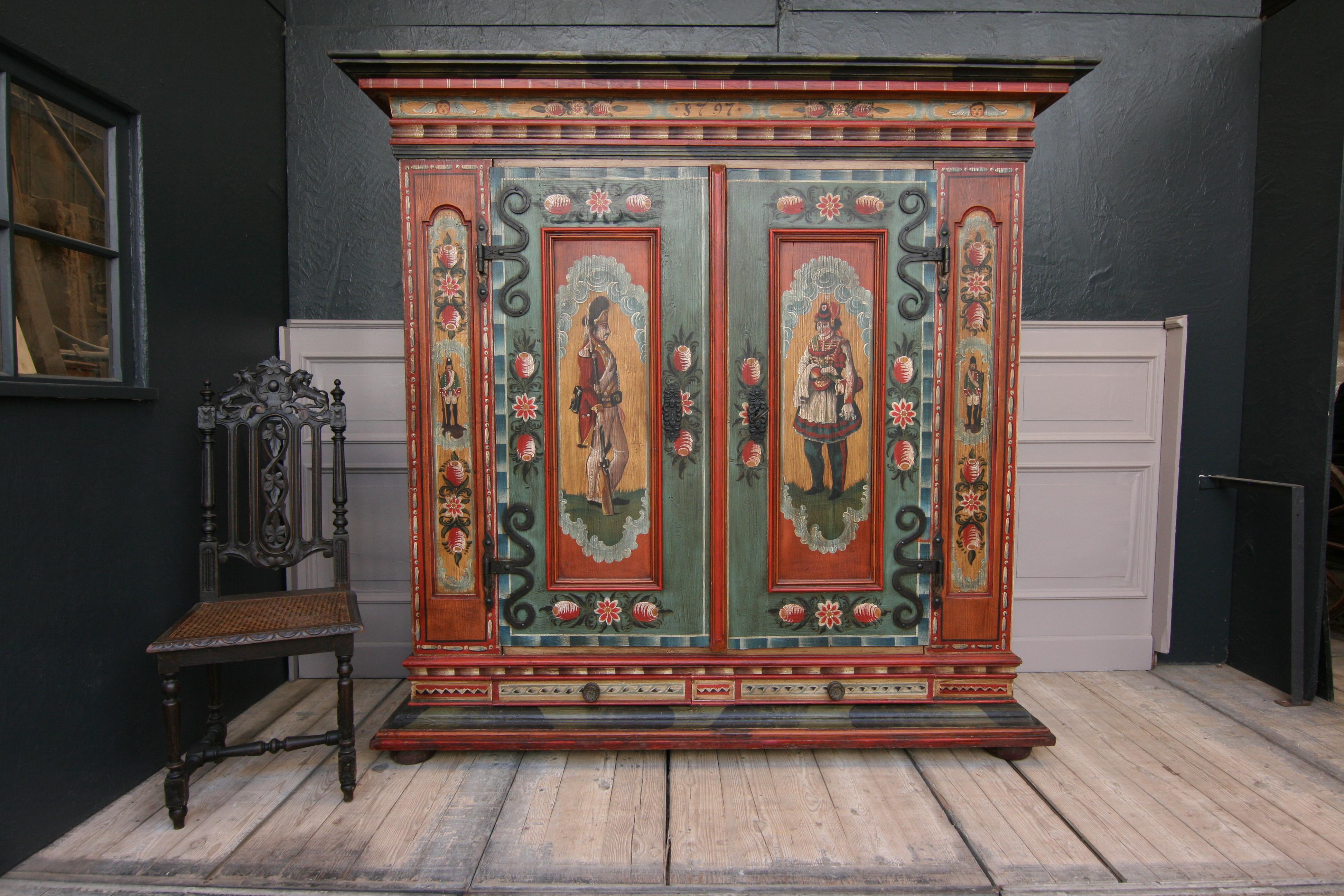 Exceptional painted cupboard, from circa early 20th century. Made of solid pine.
The special feature of this cabinet is the double doors, which can be opened with bolts. They show soldiers in uniform (see pictures). Also noteworthy is the lock,