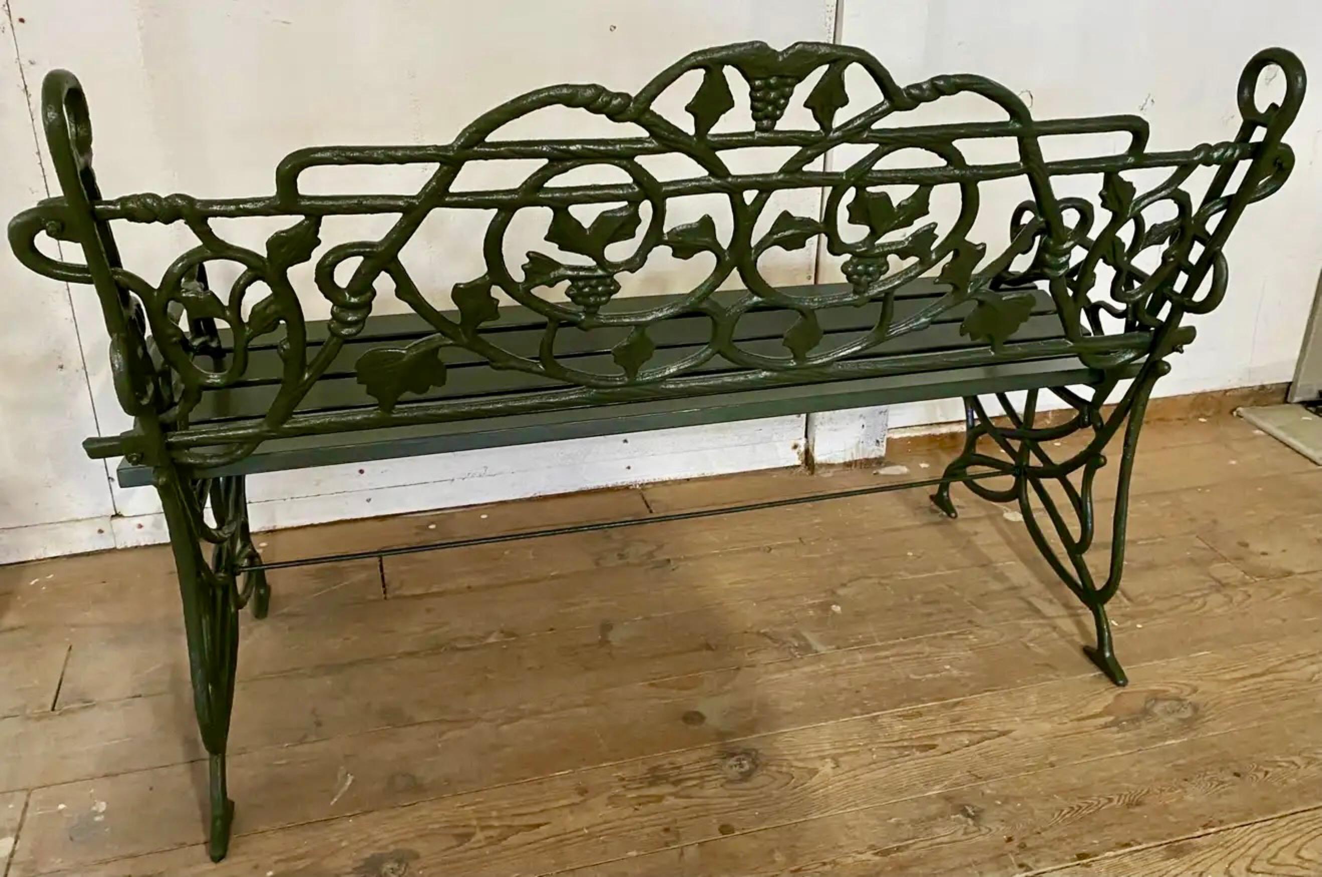 This wonderful cast iron bench stands on carved scrolled painted iron supports with backs decorated in trailing grape leaf and vine motif. Newly re-painted and restored, ready to be placed in any garden or outdoor area for a dramatic