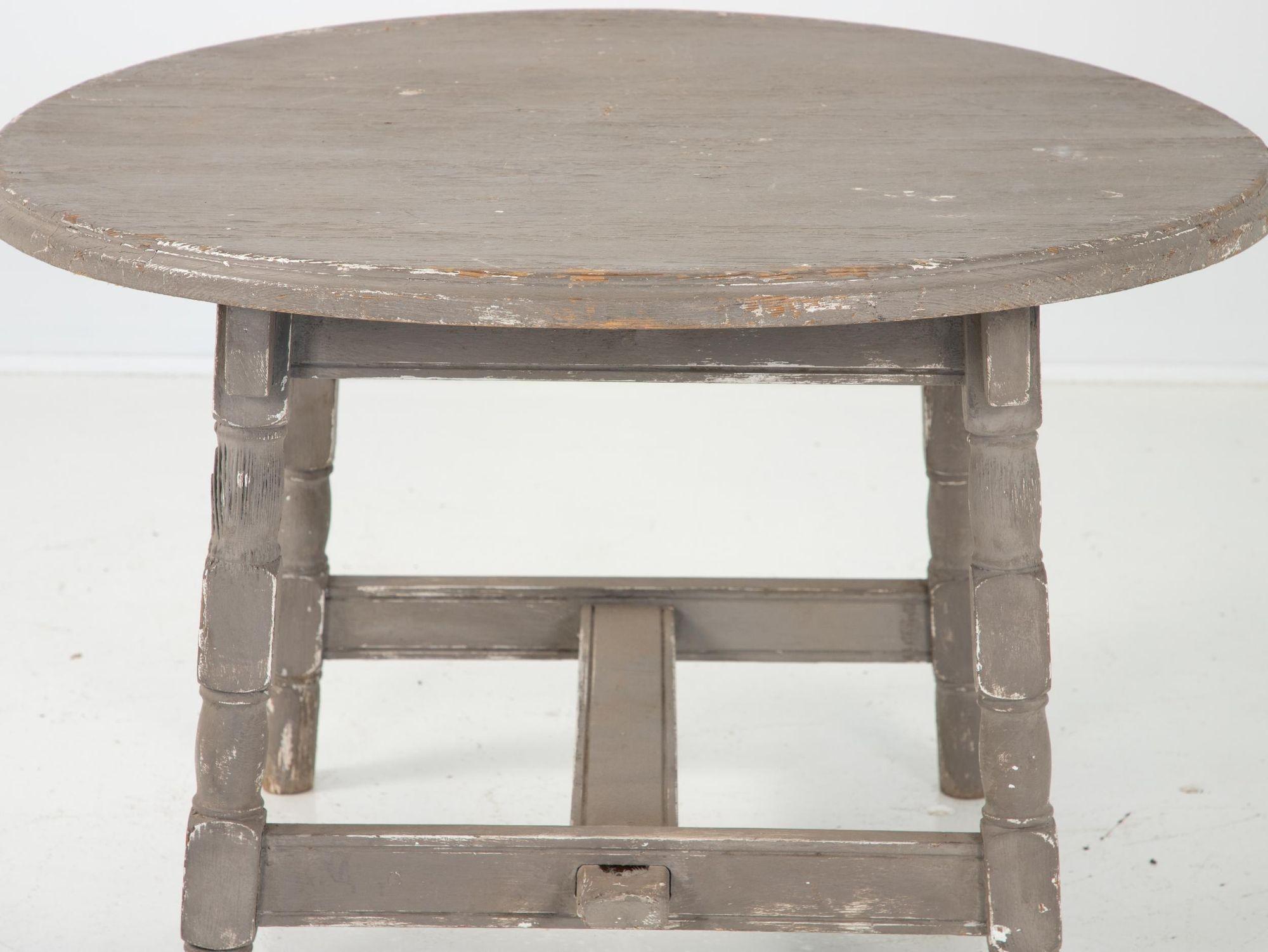 A painted grey low table in a rustic country style. Stretcher across four legs. Early 20th century with recent paint. The top needs to be repaired as it is bowed.