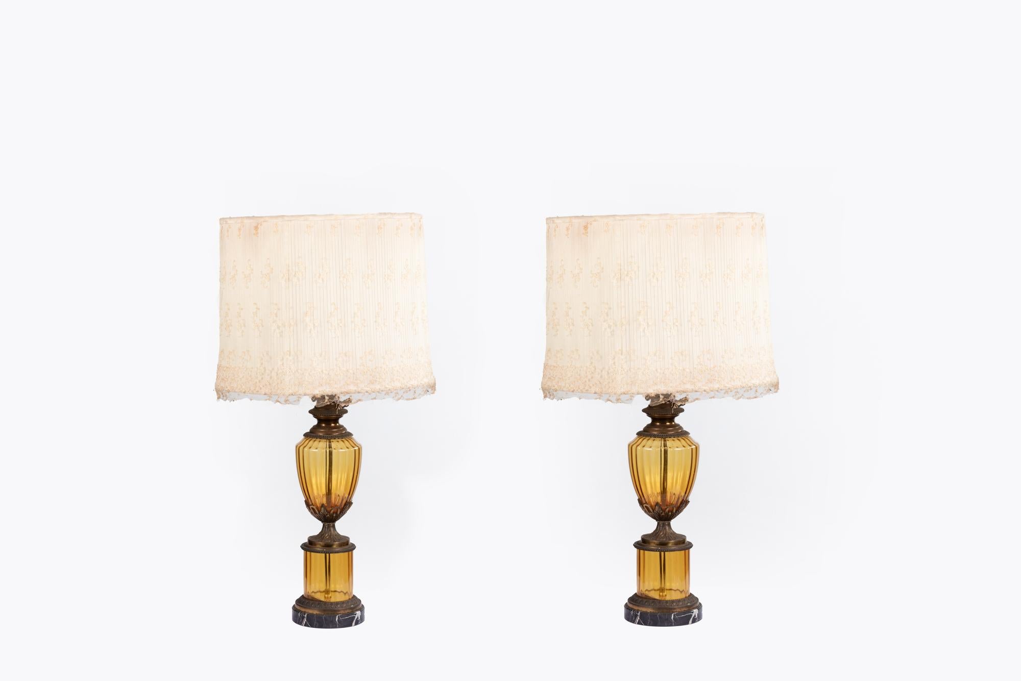 Early 20th Century pair Amber glass and bronze lamps standing on black veined marble circular bases.