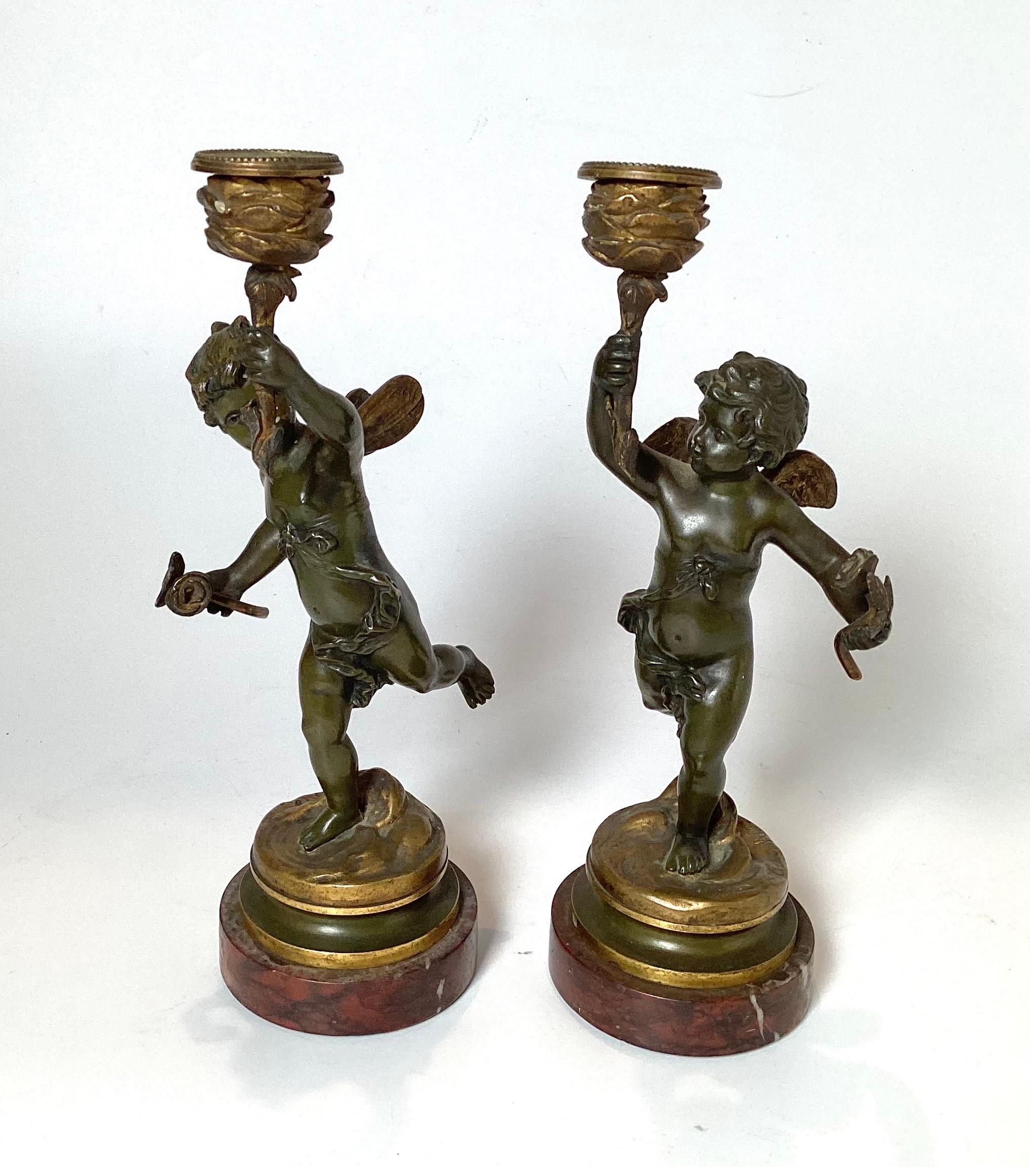 Early 20th Century Pair of bronze Cherub candlesticks on marble bases with great  warm aged patination. Great detail and signed by artist on bases.