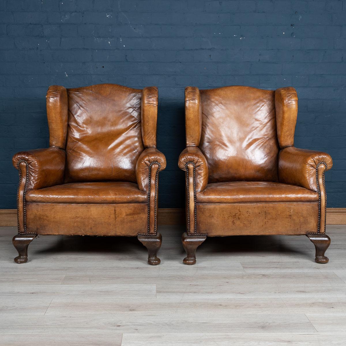 Antique early 20th century wonderful pair of leather wing back armchairs, these chairs were realised by the finest Dutch craftsmen, the solid wood frame upholstered in superb quality leather which over the years have only gained in class and style.
