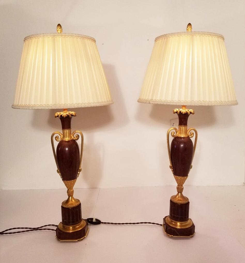 Classic pair of doré bronze mounted rouge marble urn lamps are signed on the bottom 