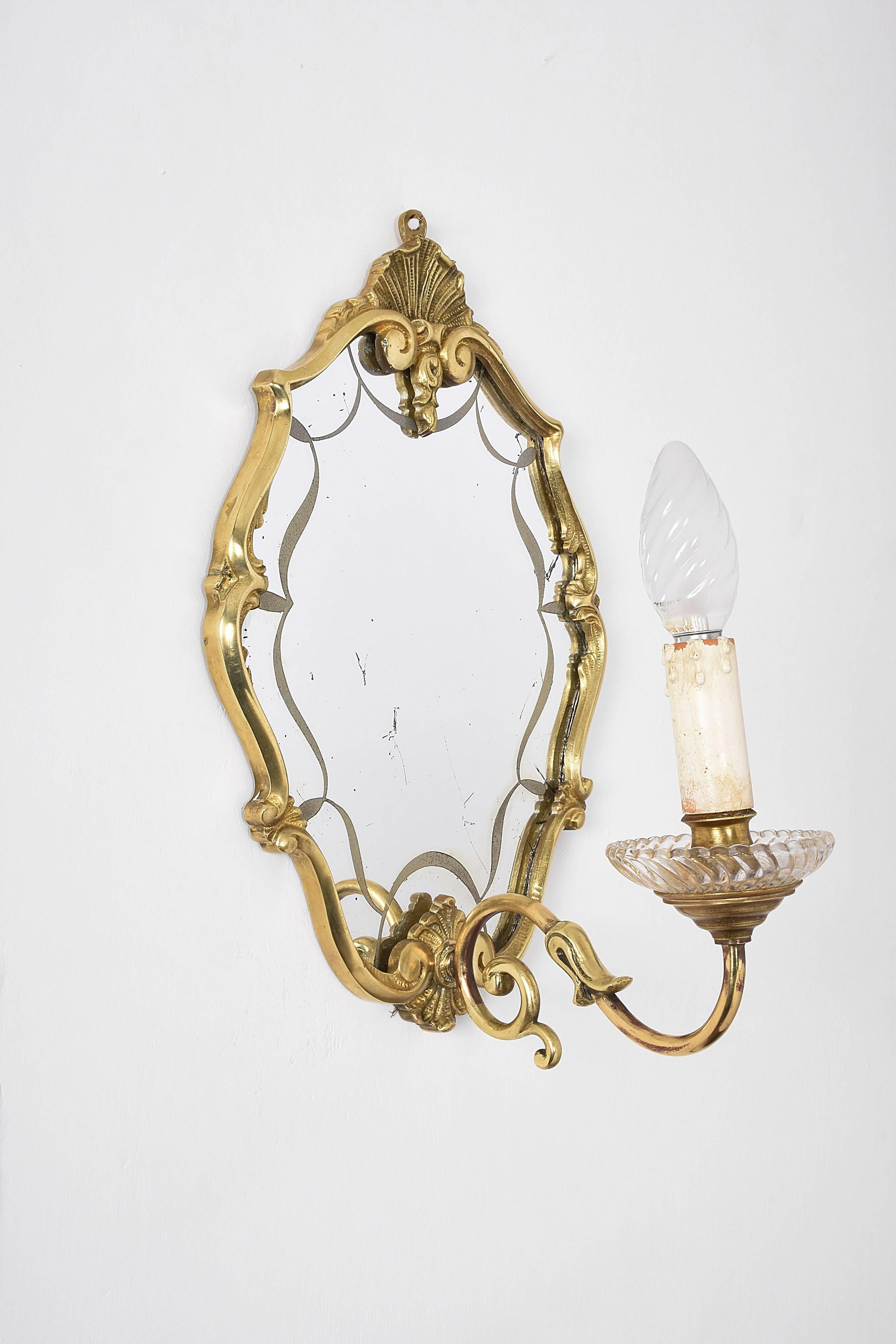 Early 20th century pair of Italian decorative brass wall lights with mirror. This is a production of the first decade of the century in Venice, and the design recalls heavily the Venetian tradition.

These wall mirrors are both in very good