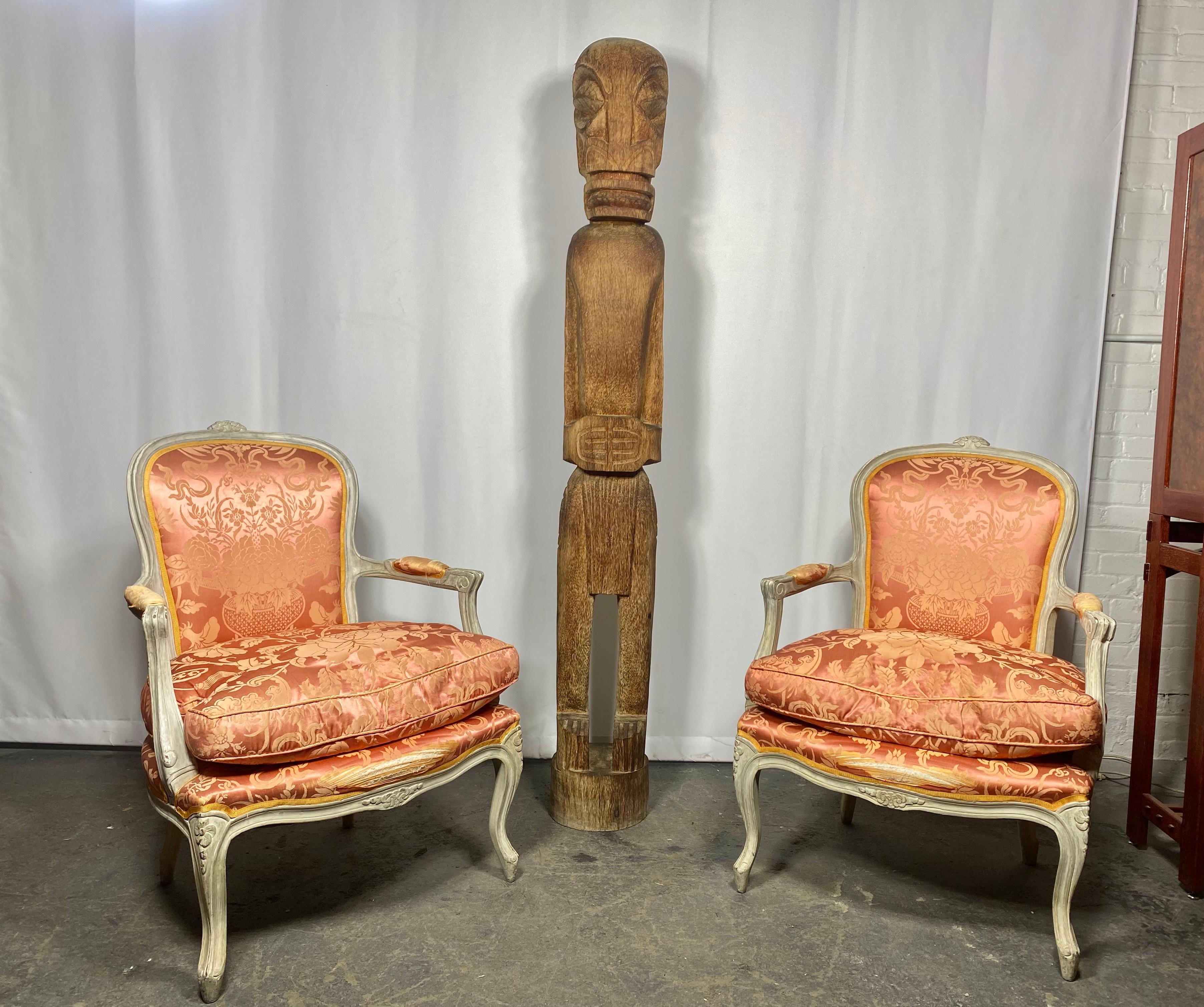 Pair of stunning carved Louis XV period bergères. Each chair features hand painted wood frames, a curved back, topped with a carved floral crest. This back flows seamlessly into the open scrolled arms with padded elbow rests and separate seat