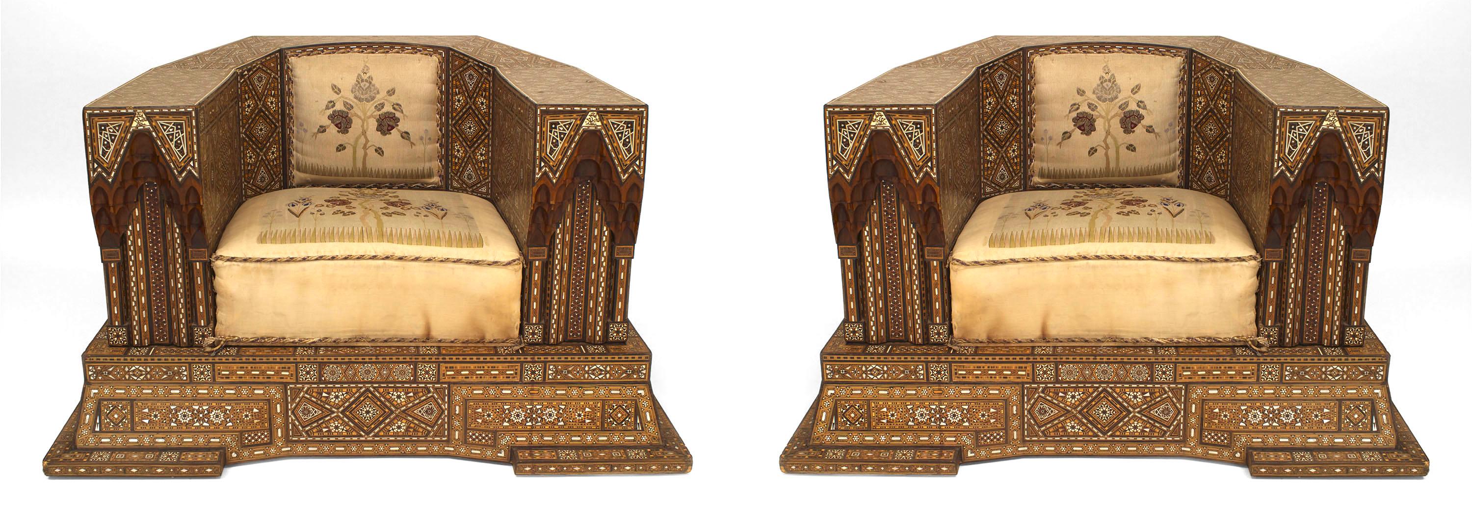 Pair of Syrian or Moorish club chairs dating to the first half of the twentieth century. Each oversized chair features canted back corners, an embroidered seat and back cushion, as well as inlaid geometric decorations of mother of pearl, bone, and