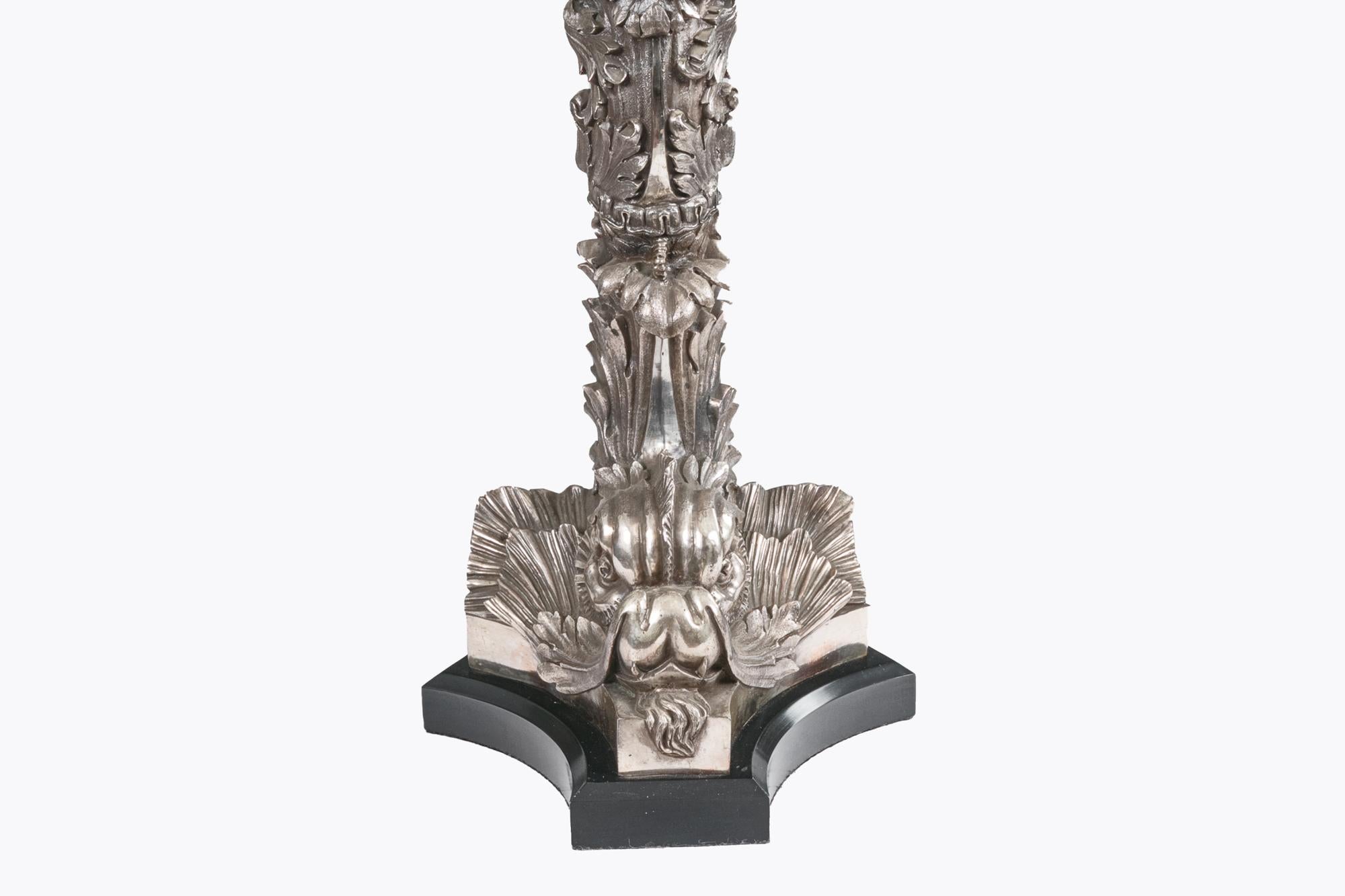 Coppia di lampade da tavolo in bronzo argentato dei primi del Novecento a forma di delfino con dettagli in foglie d'acanto. Heldly è appoggiato su basi di marmo nero. C. 1920