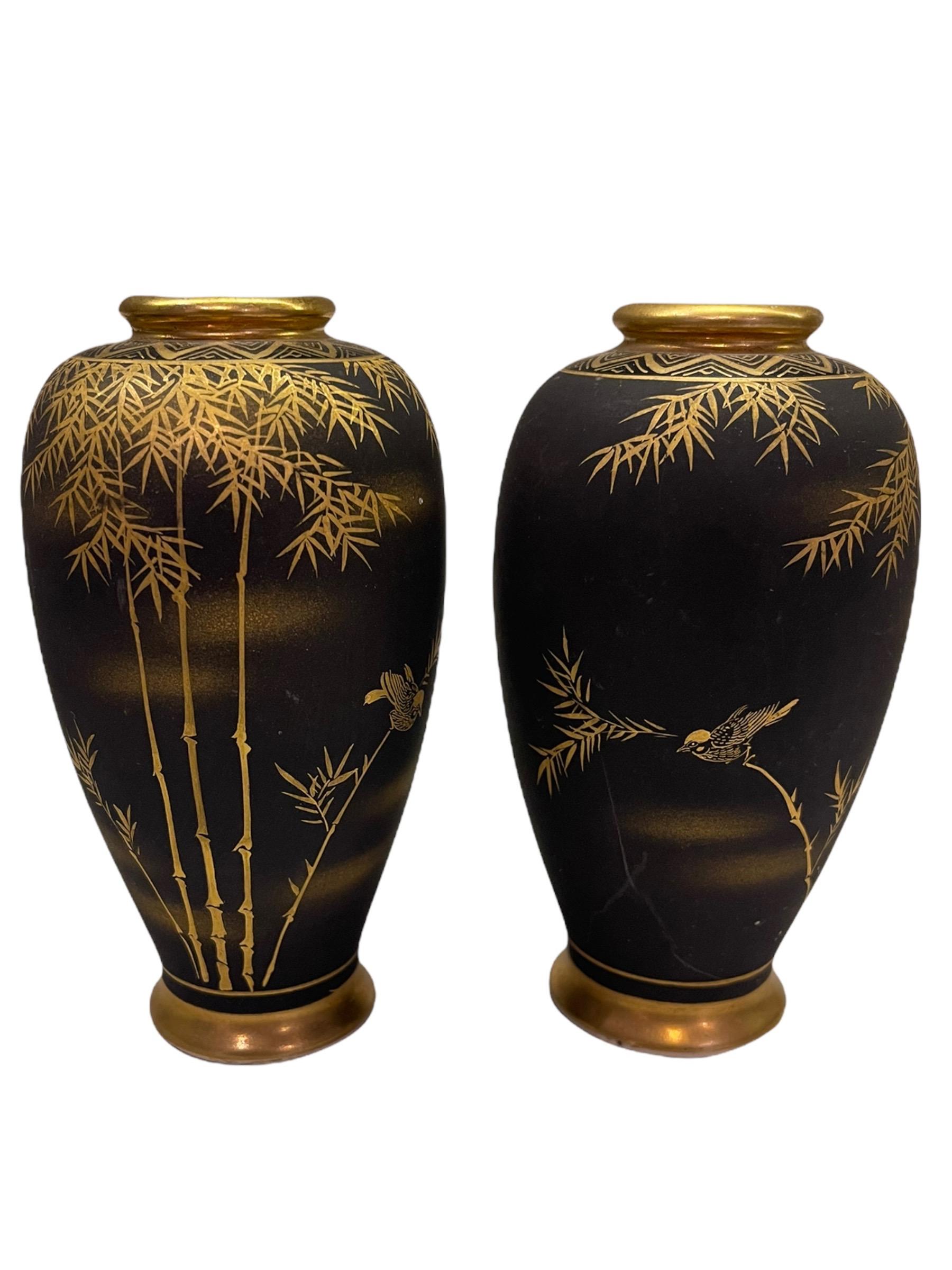 Early 20th century pair of small Japanese Kutani Porcelain Damascene vases. They are black, matte ground, and hand painted gold tone scenes of bamboo. These are signed in characters on the base.