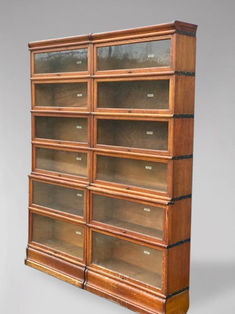 A pair of solid oak antique single waterfall Globe Wernicke 8 section Bookcases from Glasgow University. Moulded cornice top above 6 glazed sections with original glass doors, original mechanism and original brass knob handles, standing on a moulded