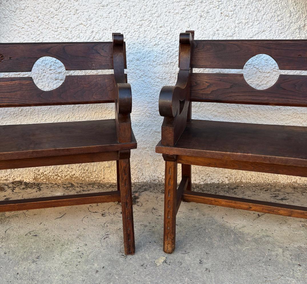 Presentamos un elegante par de bancos hechos a mano, de madera maciza de roble con pátina oscura, cuyo diseño evoca con sobriedad la estética funcional y noble de los muebles de entrada o comedor europeos de principios del siglo XX. El respaldo está