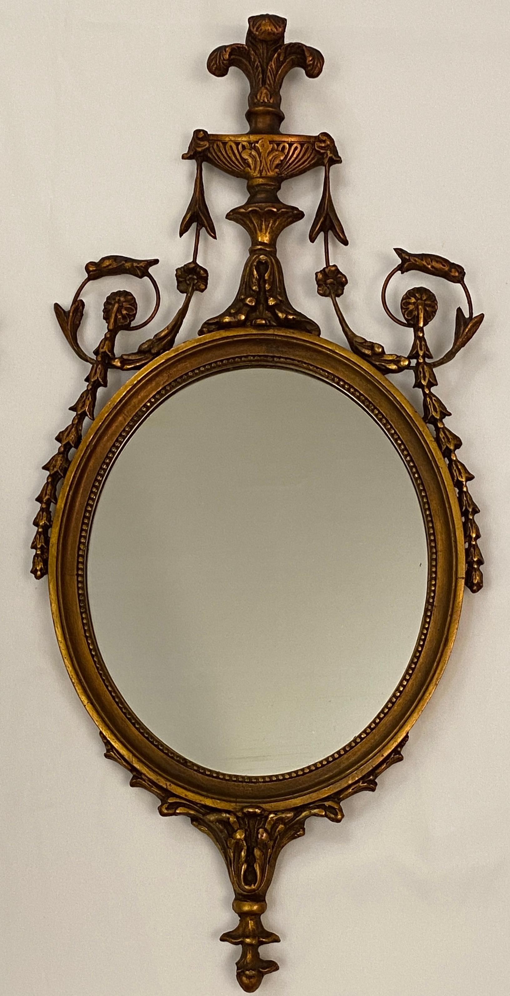 A pair of Victorian style gilded oval mirrors. The symmetrically realized mirrors feature an exquisite ornamentation inclusive of decorative garlands and rocailles.

Beautiful hand-carved details throughout this pair of Victorian style mirrors will
