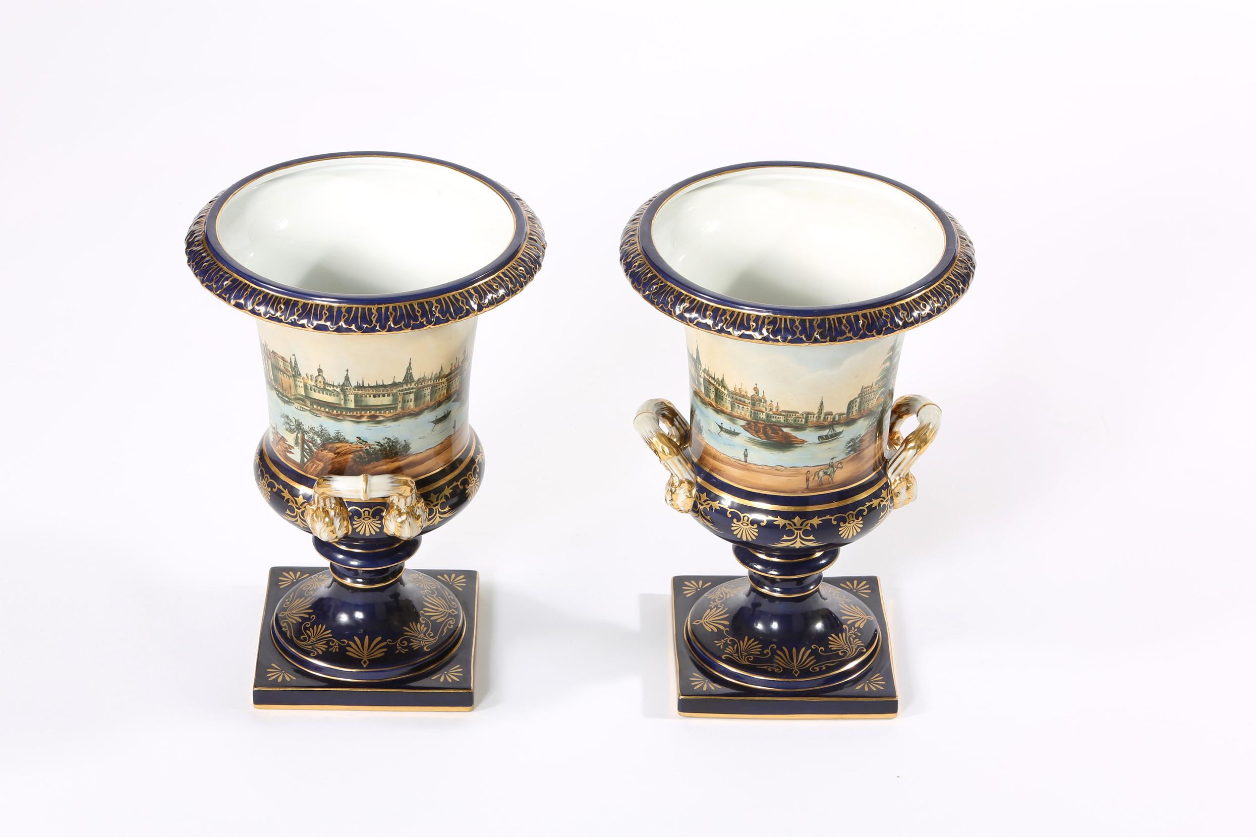 Early 20th century pair porcelain decorative urns / campana shaped vases with gilt gold side handles and exterior design details. Each vase is in great vintage condition. Minor wear consistent with age / use. Maker's mark undersigned. Each vase